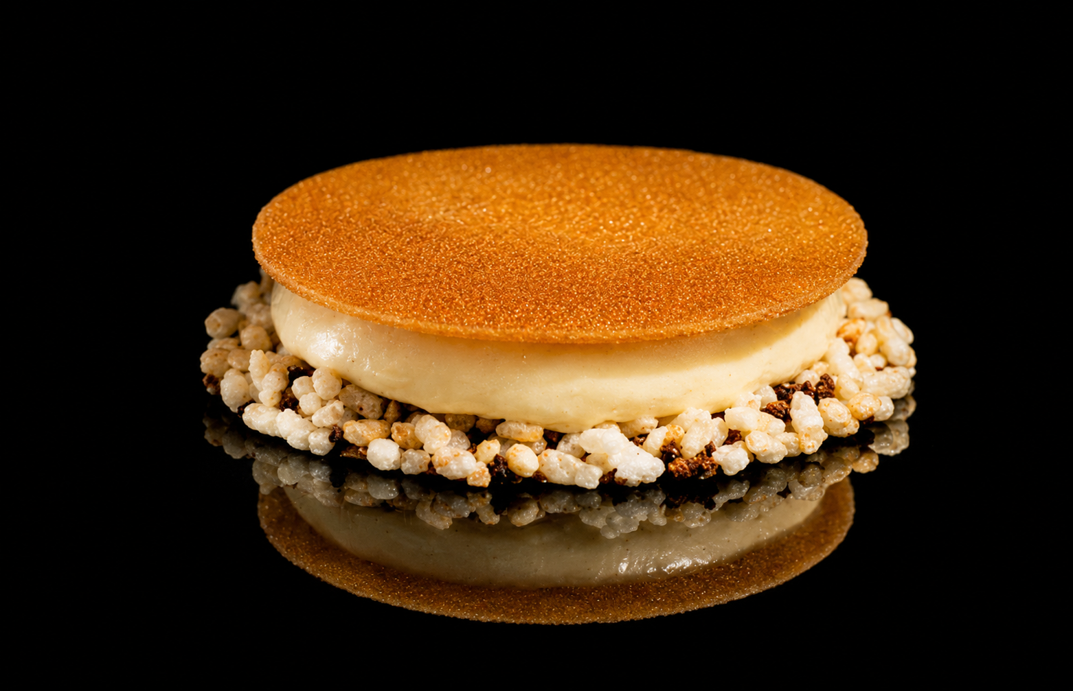 Gâteau de biscuit, crème et riz soufflé, présenté sur un fond noir
