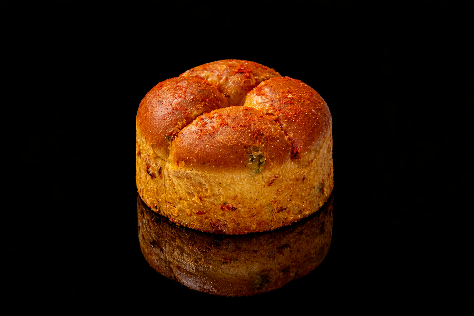 Une boule de viande farcie en croûte dorée, posée sur une surface noire reflet