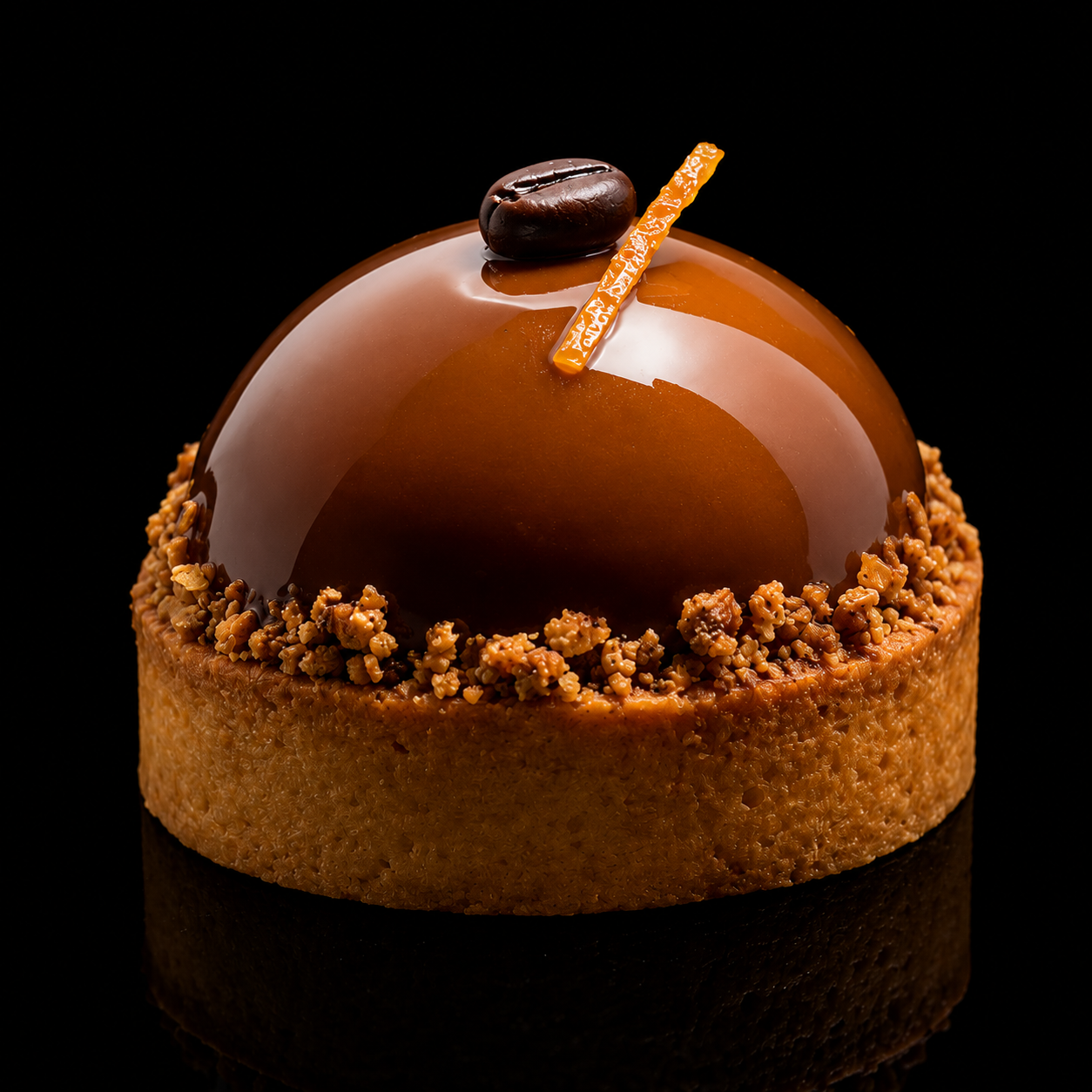 Gâteau au chocolat brillant avec une décoration de café en haut, entouré de miettes croustillantes
