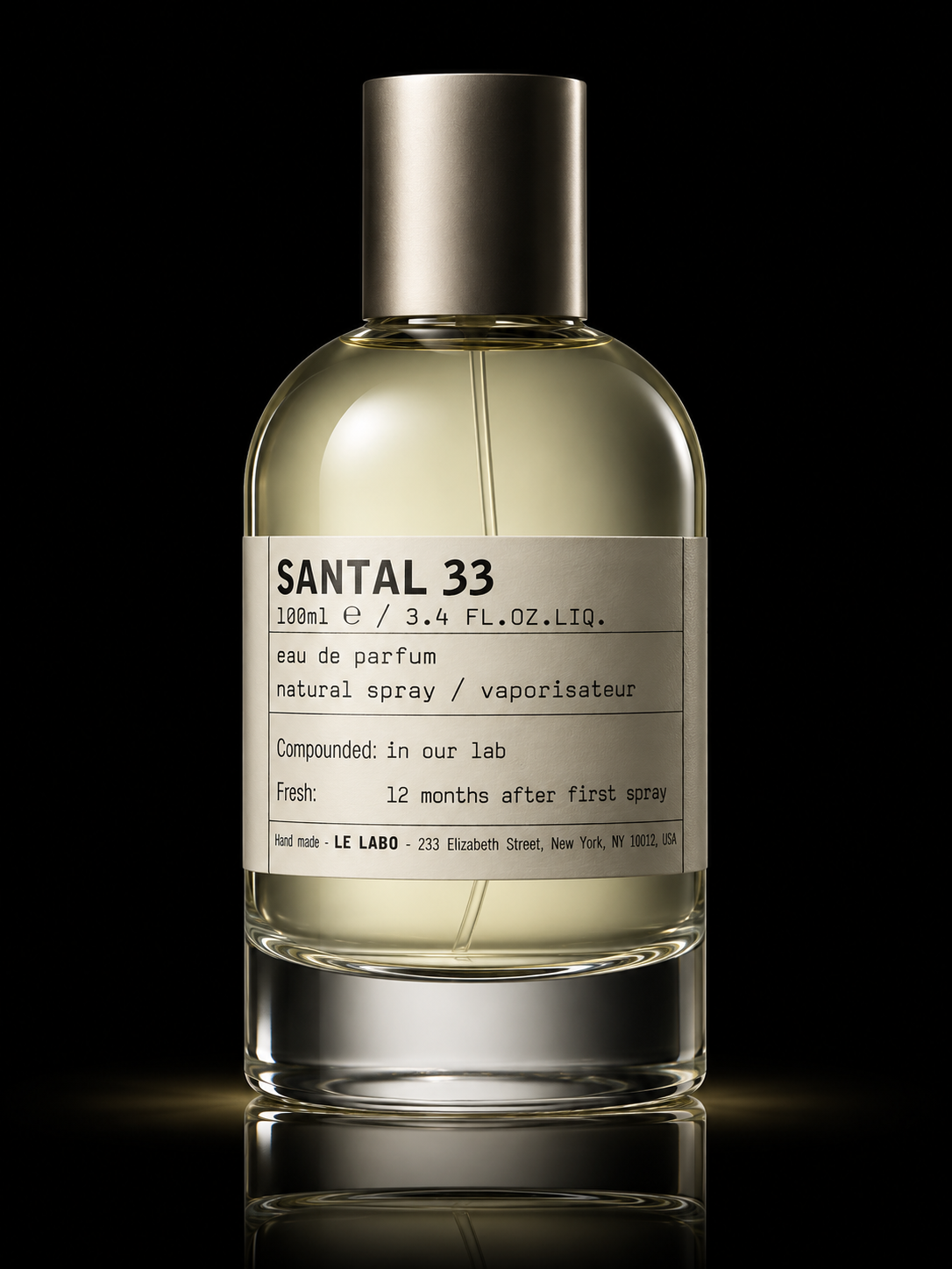 Flacon de parfum transparent avec un liquide clair, étiquette blanche avec texte en anglais et prix, fond noir.