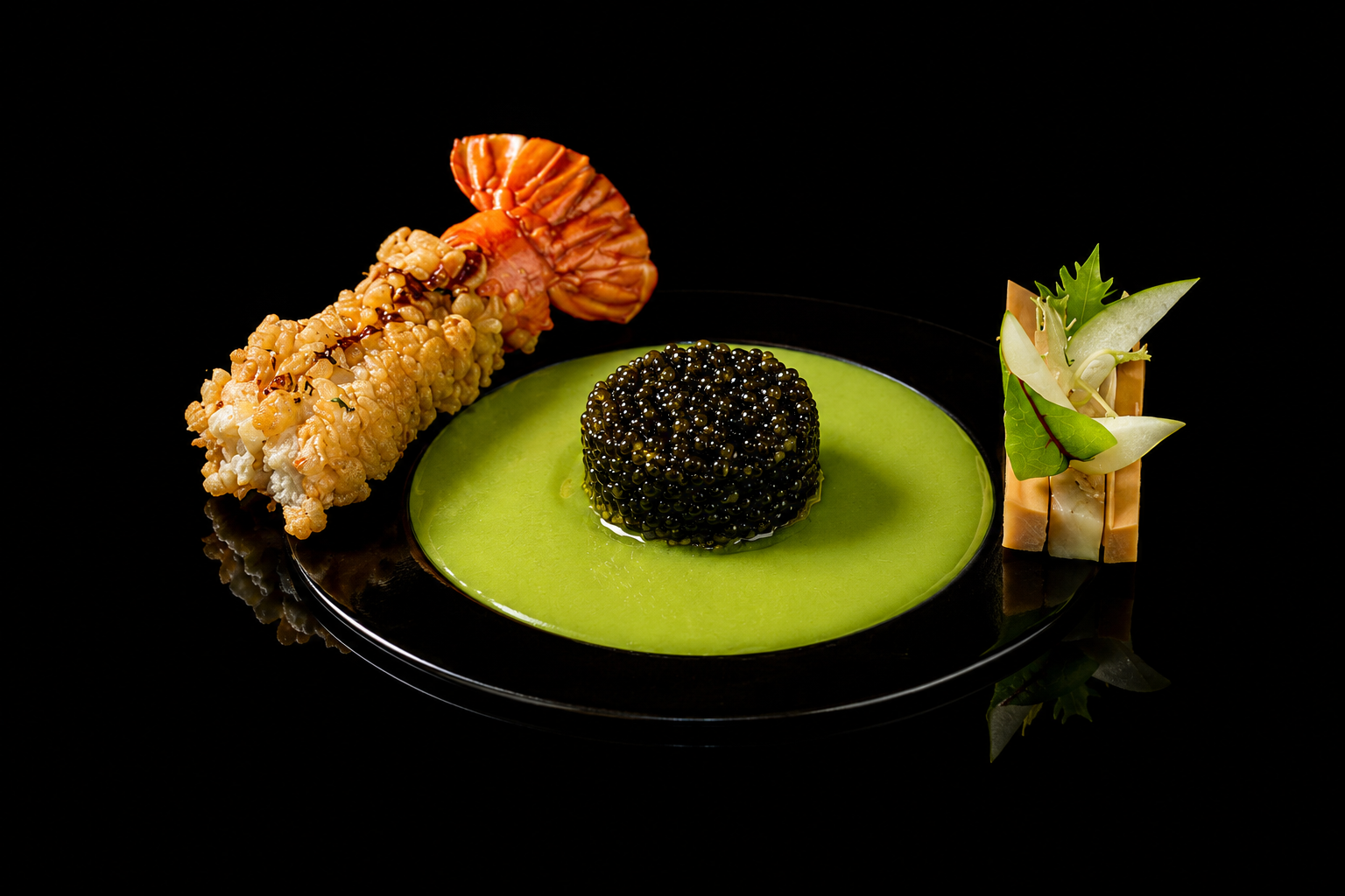 Assiette noire avec un cercle de purée verte, en son centre des œufs de lump noir, et à côté un rouleau de sushi décoré de légumes verts et de thon