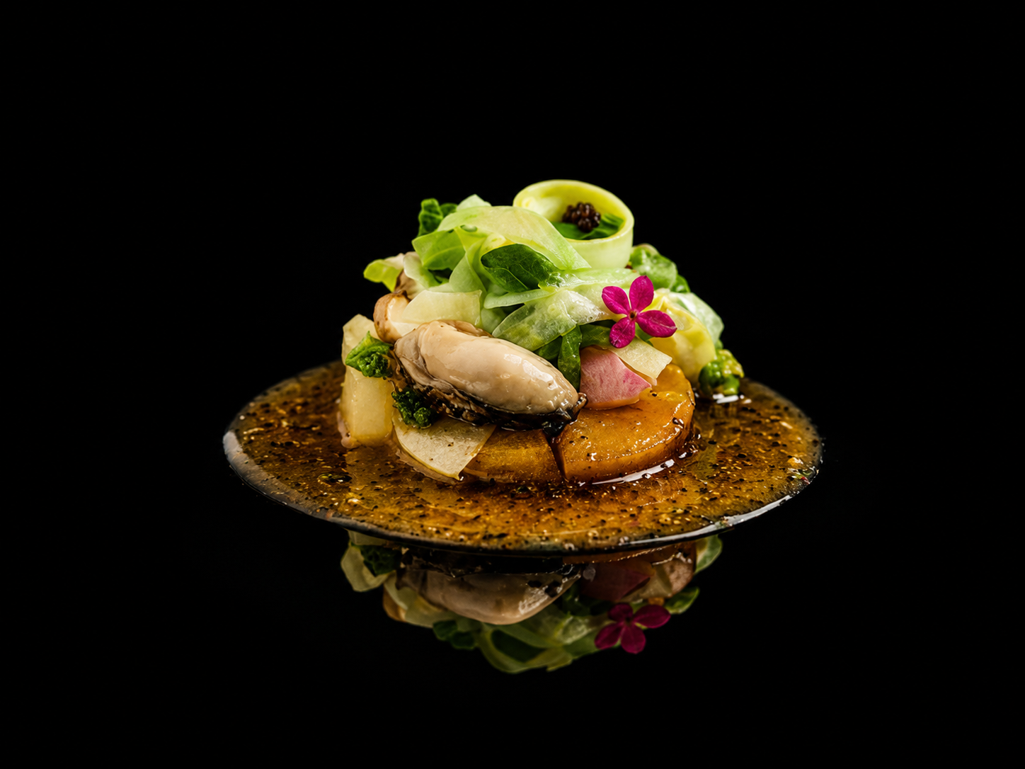 Assiette élégante avec un plat de fruits de mer et salade garnie de fleurs comestibles, sur un fond noir.