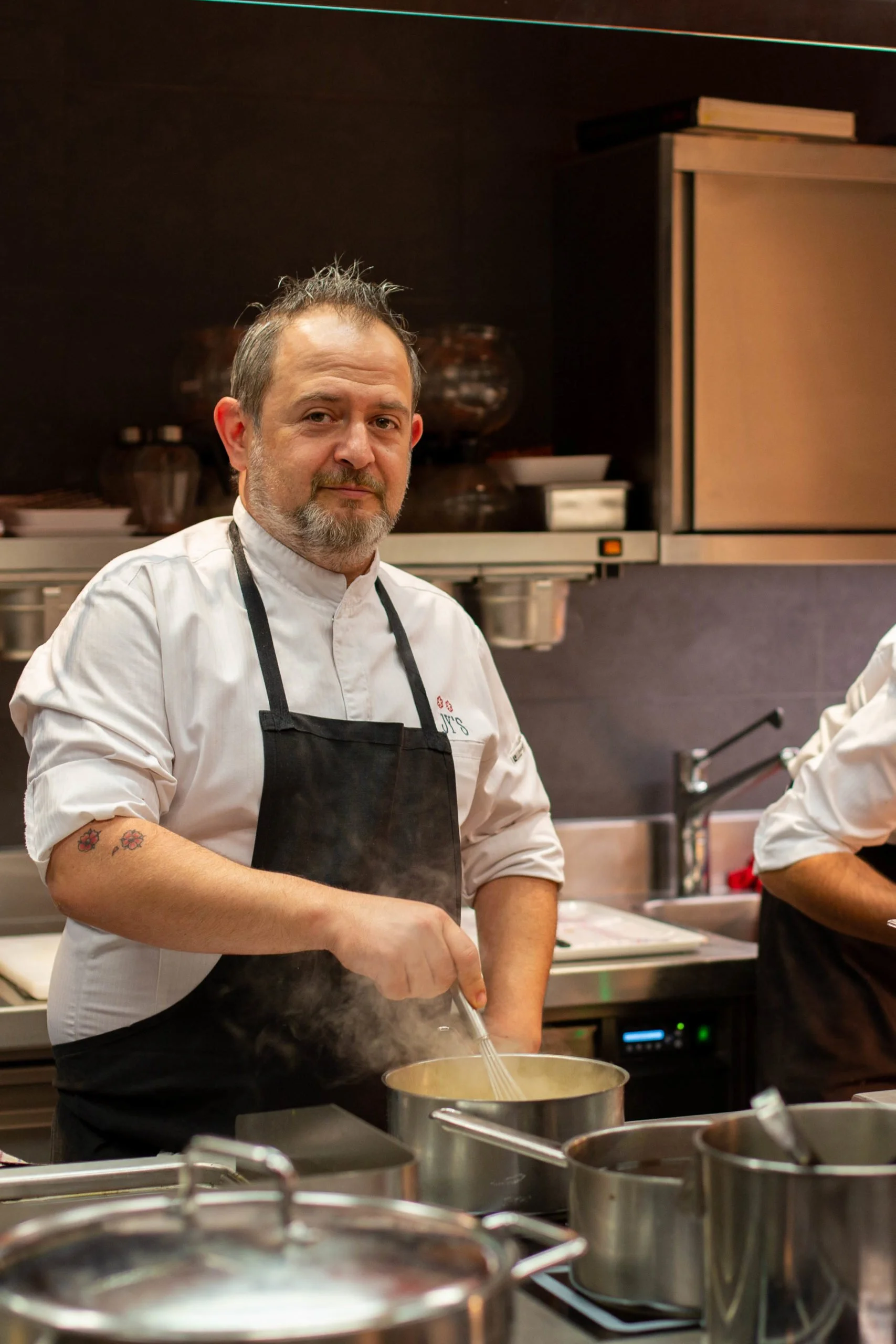 Chef en cuisine préparant une sauce dans une casserole dans une cuisine professionnelle.
