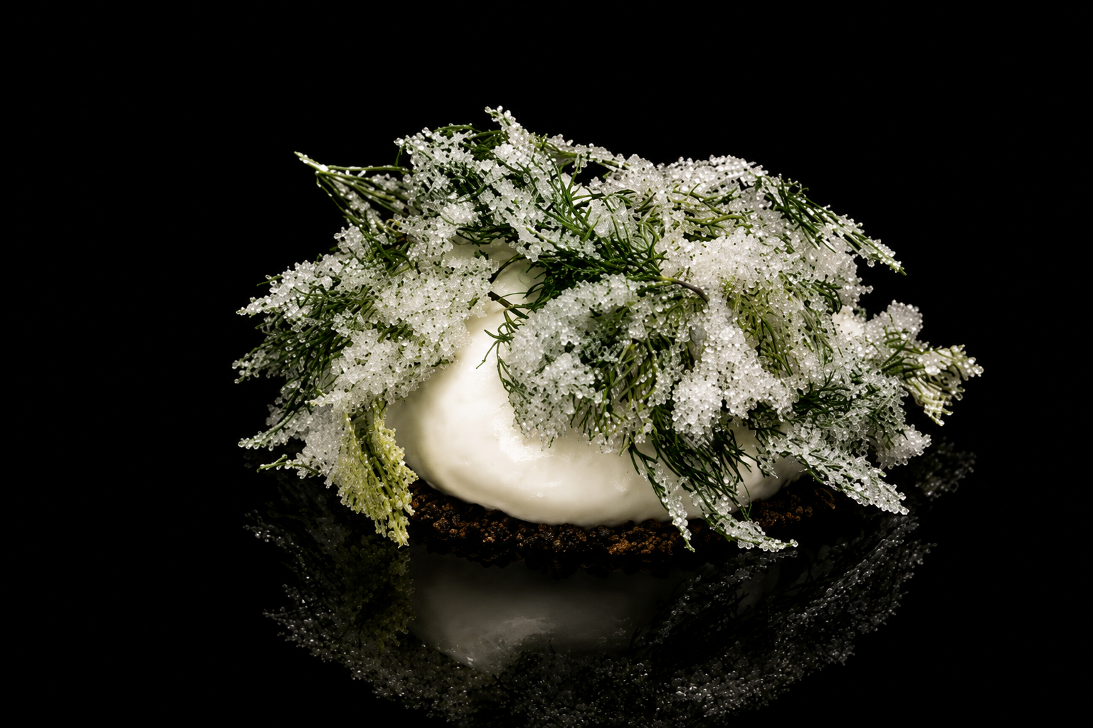 Gâteau décoré d'ornements floraux blancs et verts sur un fond noir.