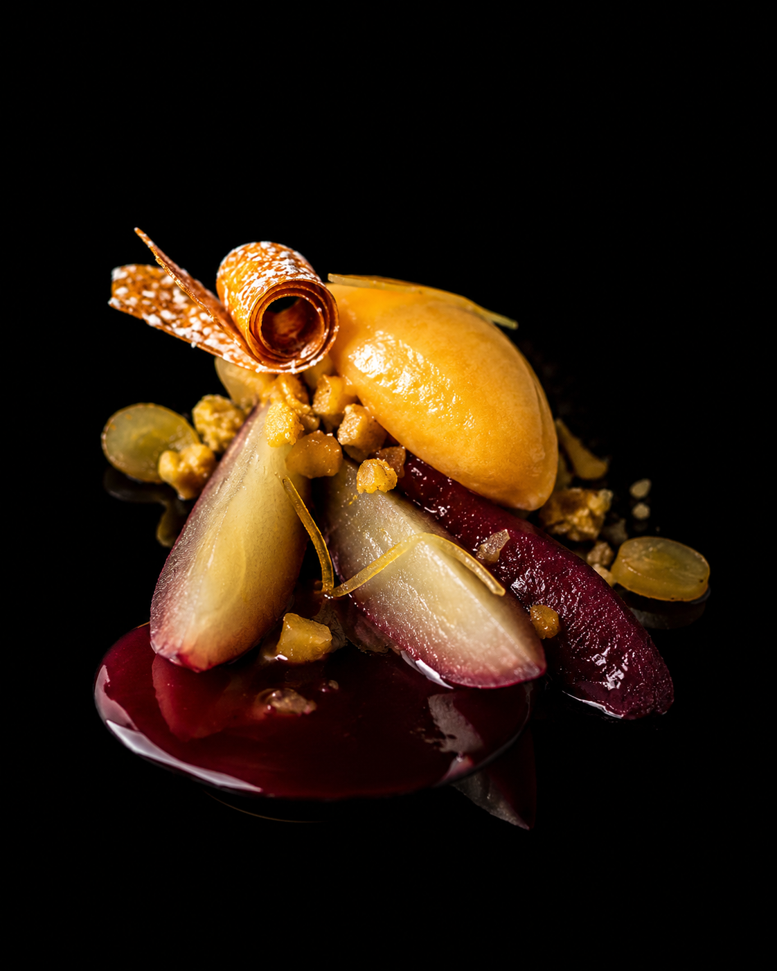 Dessert avec des morceaux de fruits, une sauce rouge et une garniture décorative en forme de rouleau.