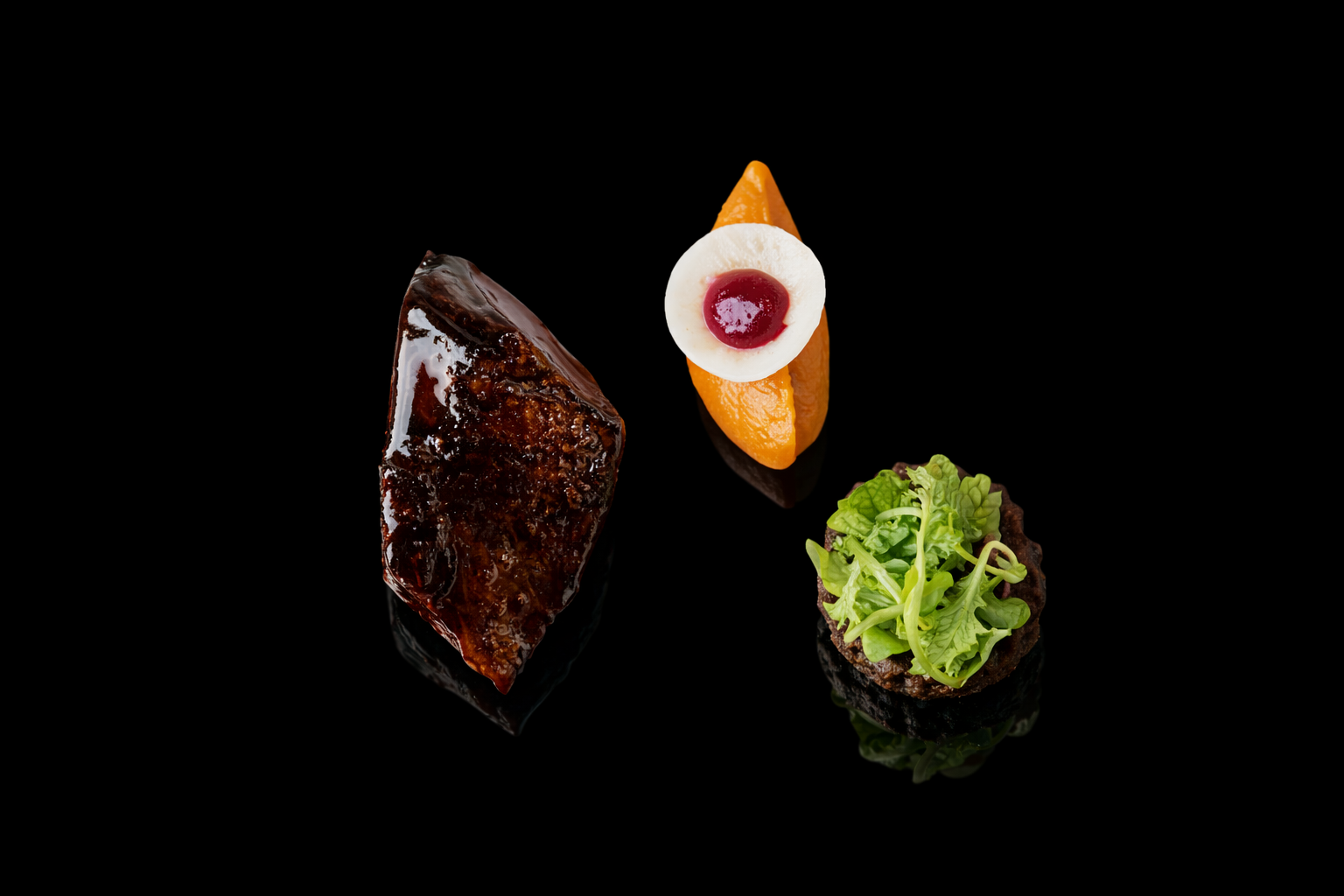 Trois amuse-bouches sur fond noir : une tranche de viande en croûte, un canapés avec une base de pain, garniture de salade et une autre est une bouchée végétarienne.