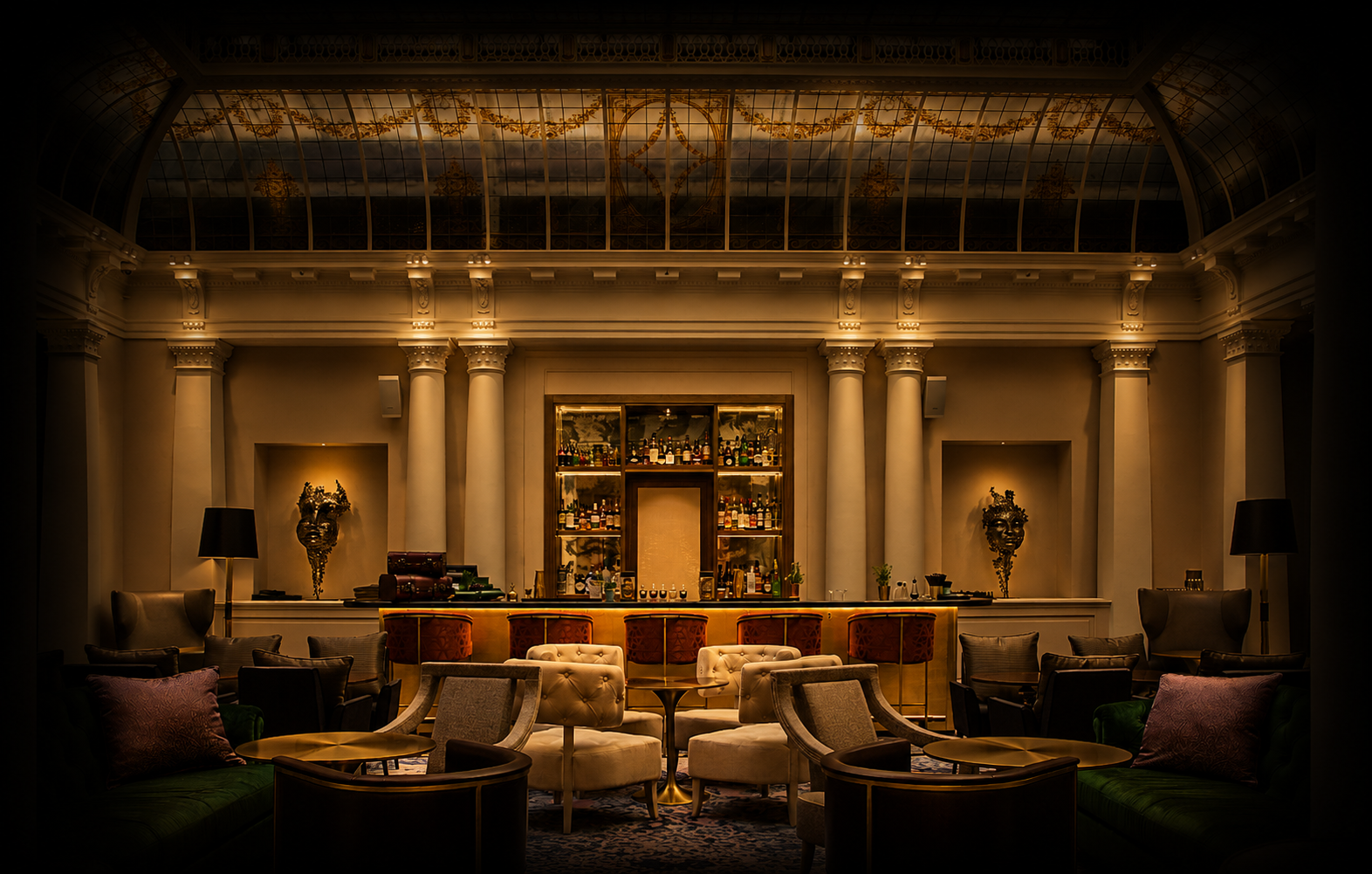 Un bar élégant avec un éclairage tamisé, des fauteuils et canapés autour de petites tables, un comptoir de bar en arrière-plan avec des bouteilles de boissons, décorations artistiques, et une verrière en plafond laissant passer la lumière