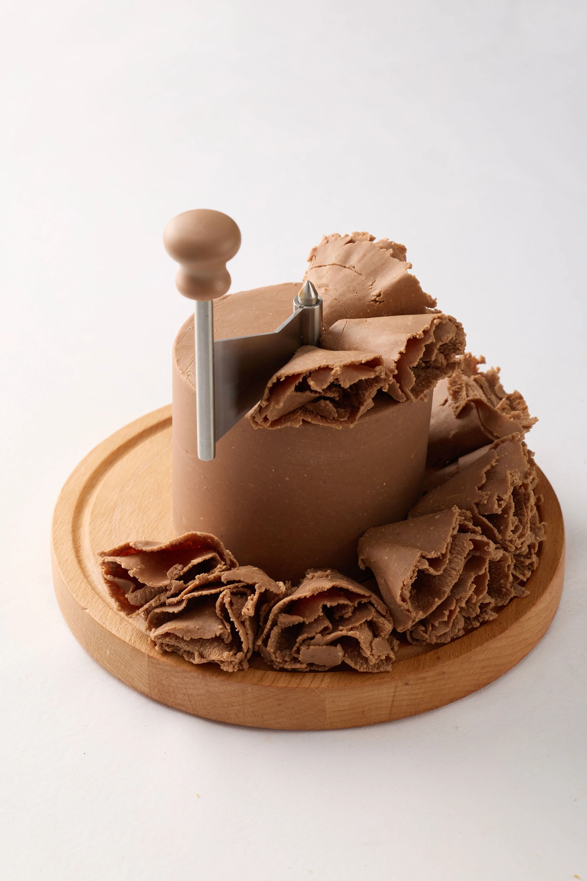 Un gâteau de chocolat avec une plaque de chocolat râpé décorative sur un plateau en bois.