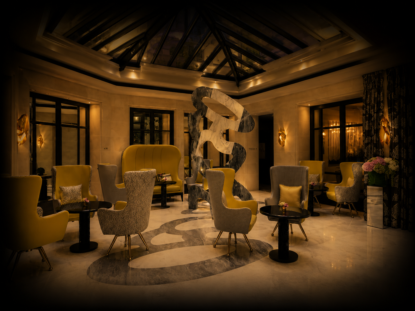 Intérieur d'un salon ou d'un restaurant sophistiqué avec fauteuils jaunes et grisés, une sculpture abstraite au centre, décor élégant avec éclairage chaud, fleurs en pot, fenêtres à double vitrage et rideaux foncés.