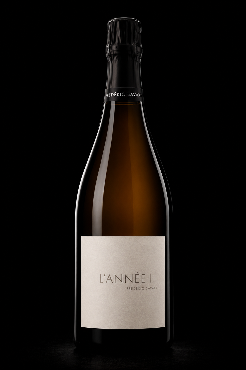 Bouteille de champagne noire avec étiquette blanche portant le nom "L'Année 1" et mention de Frédéric Savart, en arrière-plan noir.