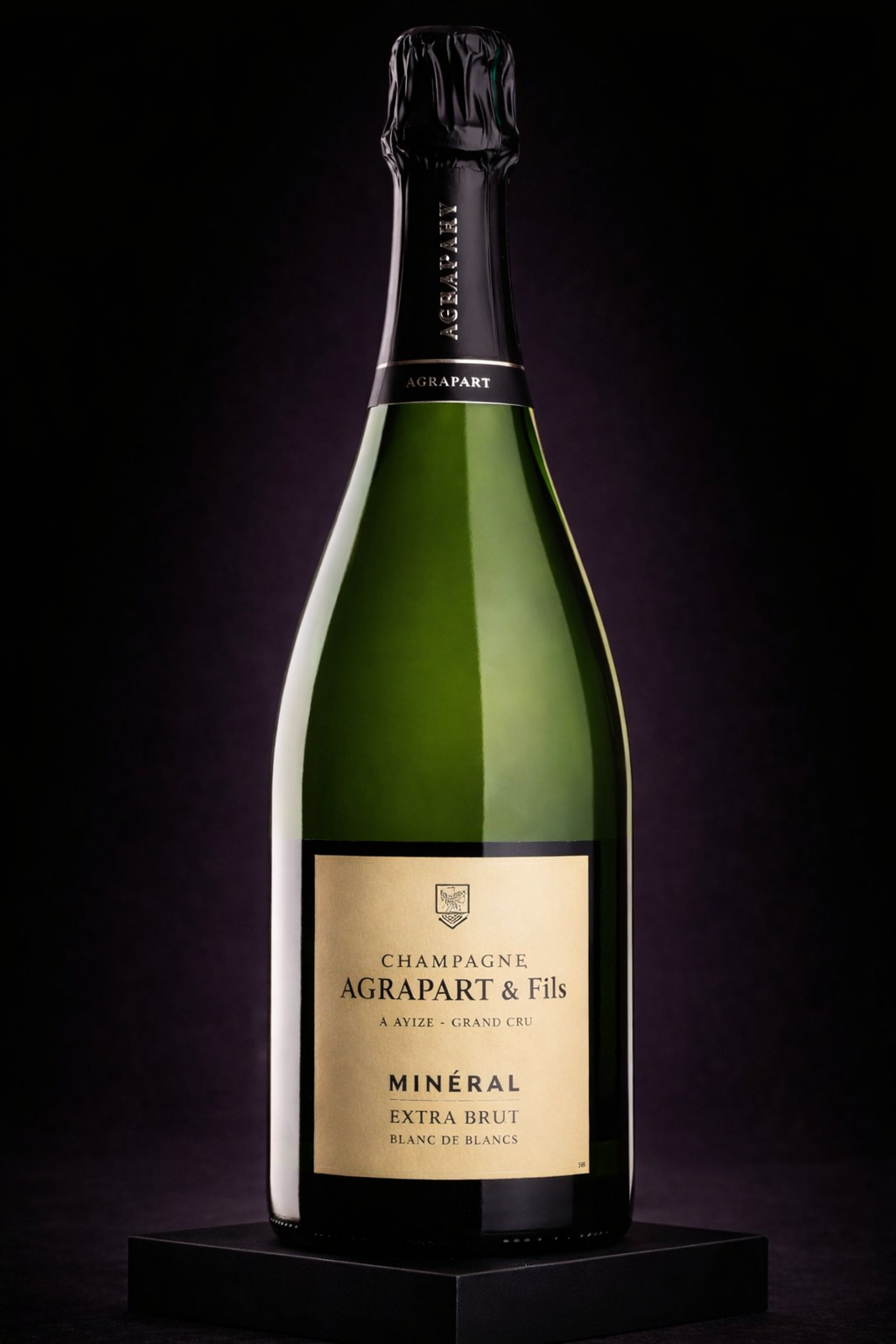 Bouteille de champagne Agrapart & Fils, Minéral Extra Brut, blanc de blancs, positionnée sur un socle noir, fond sombre.