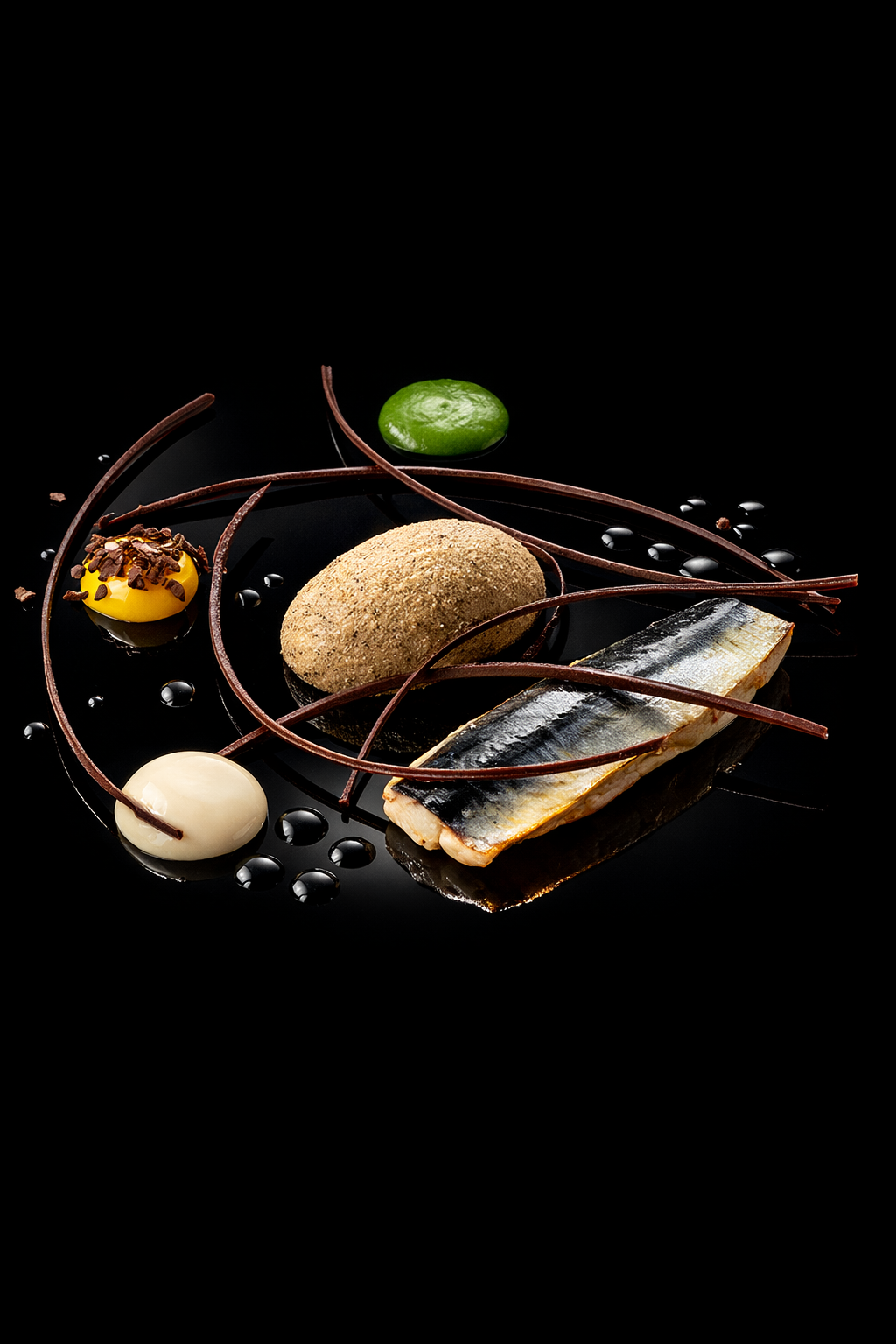 Assiette de poisson grillé avec décorations chocolatées, origami en chocolat, et diverses saveurs de sauces ou purées sur fond noir