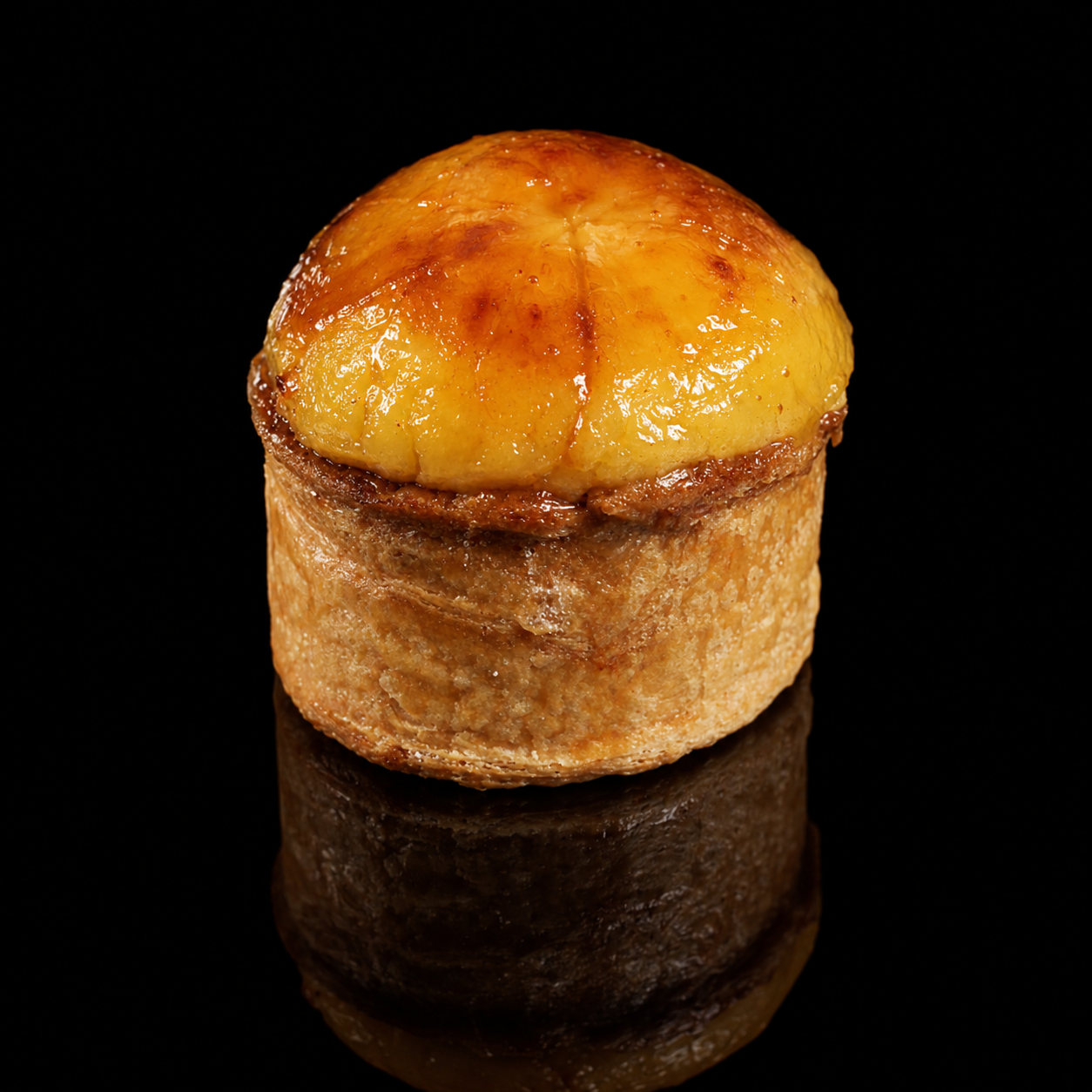 Un amuse-bouche à base de pomme de terre cuite, garnie d'une sauce ou garniture fondante, placé sur un fond noir.