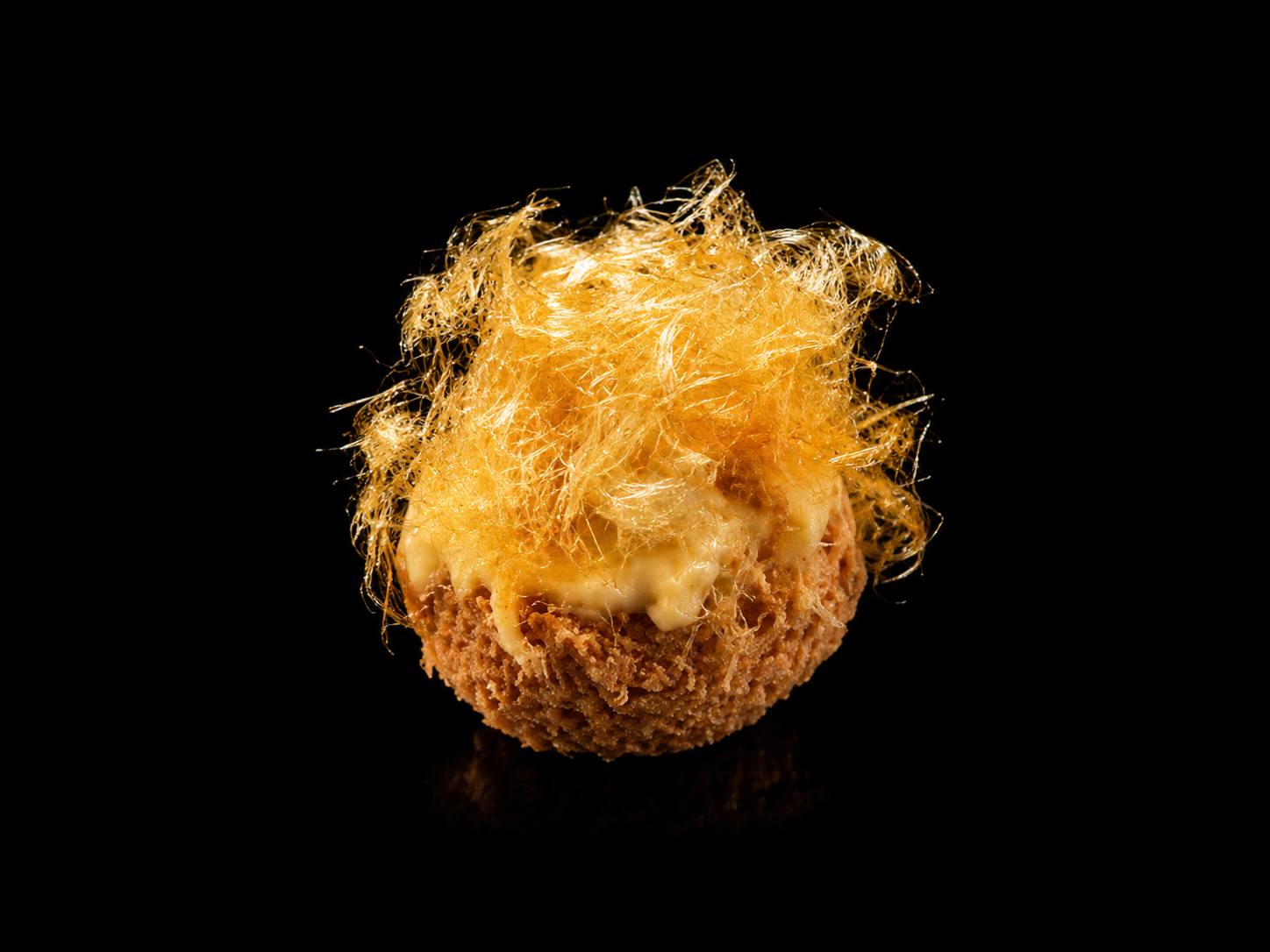 Bouchée de nourriture avec une croûte croustillante, garnie de fromage fondant et de filaments de fromage grillé, sur un fond noir