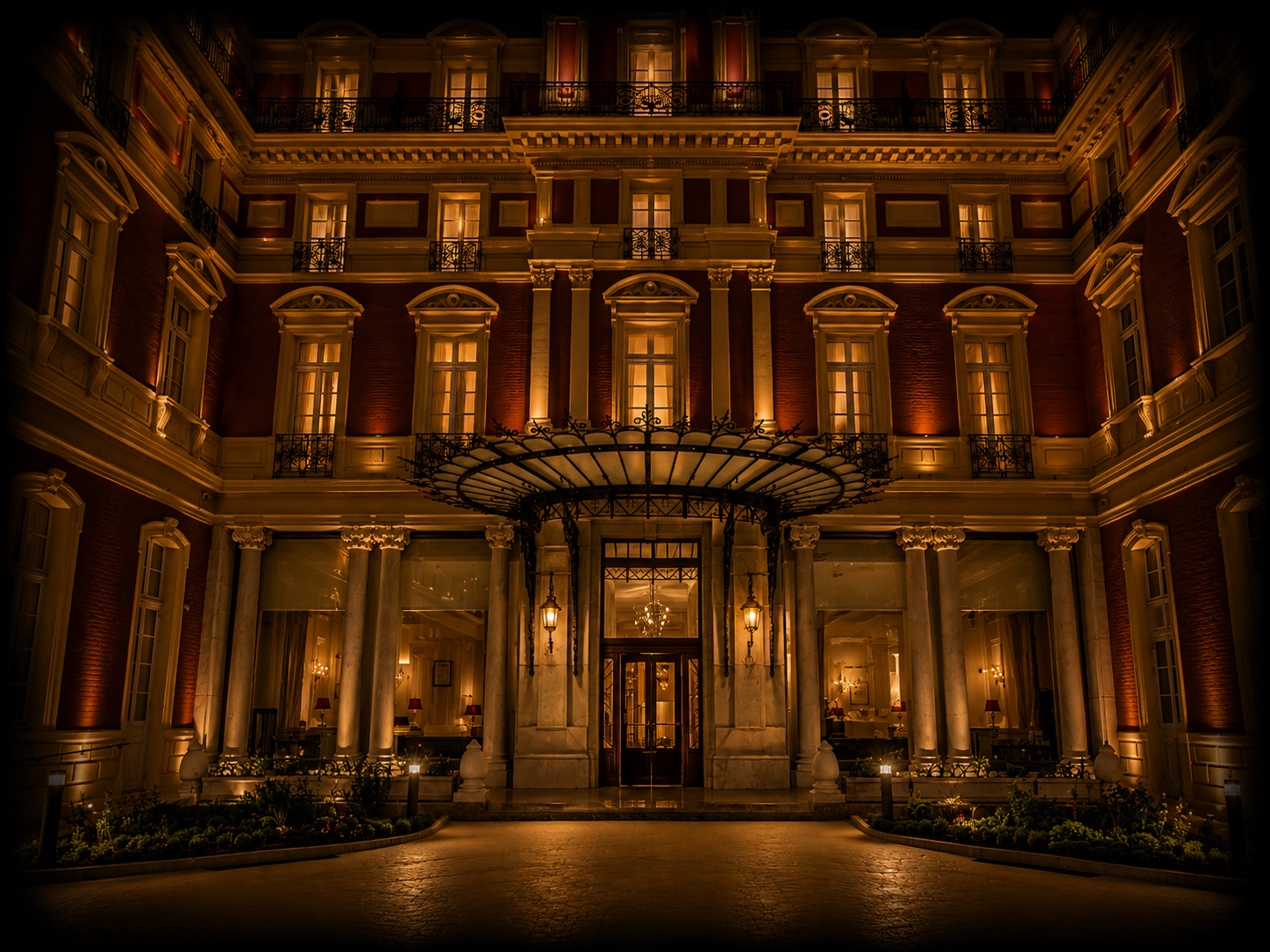Façade éclairée d'un hôtel de style classique avec colonnes et fenêtres illuminées la nuit.