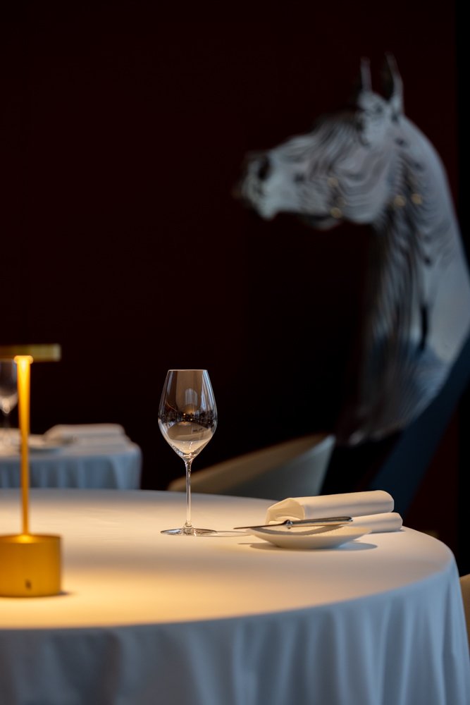 Table élégante avec un verre à vin, une assiette et des couverts, décorée d'une lampe dorée, avec une peinture d'un zèbre en arrière-plan