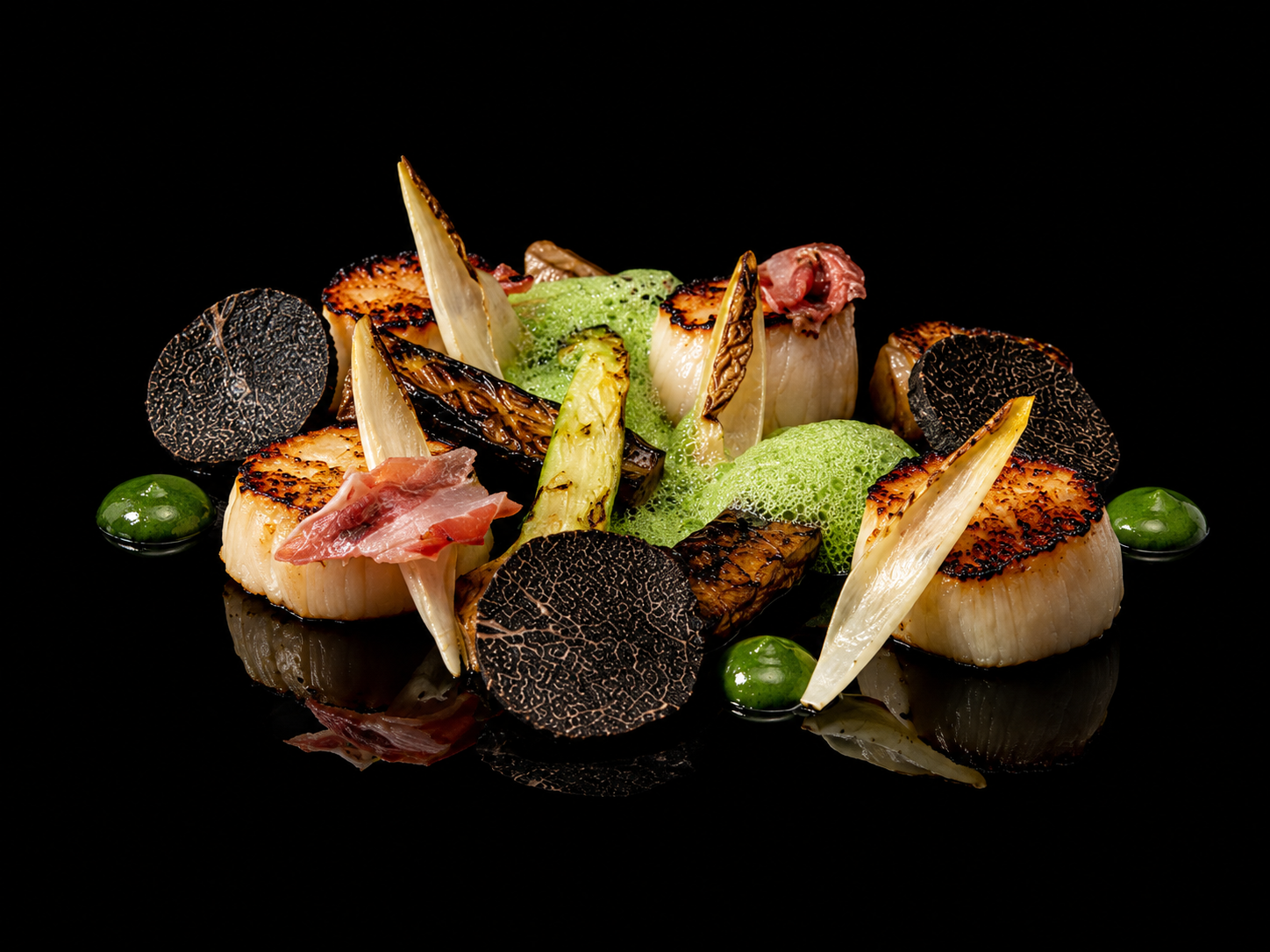 Assiette gastronomique avec coquilles Saint-Jacques, champignons noirs, légumes grillés et espuma vert.