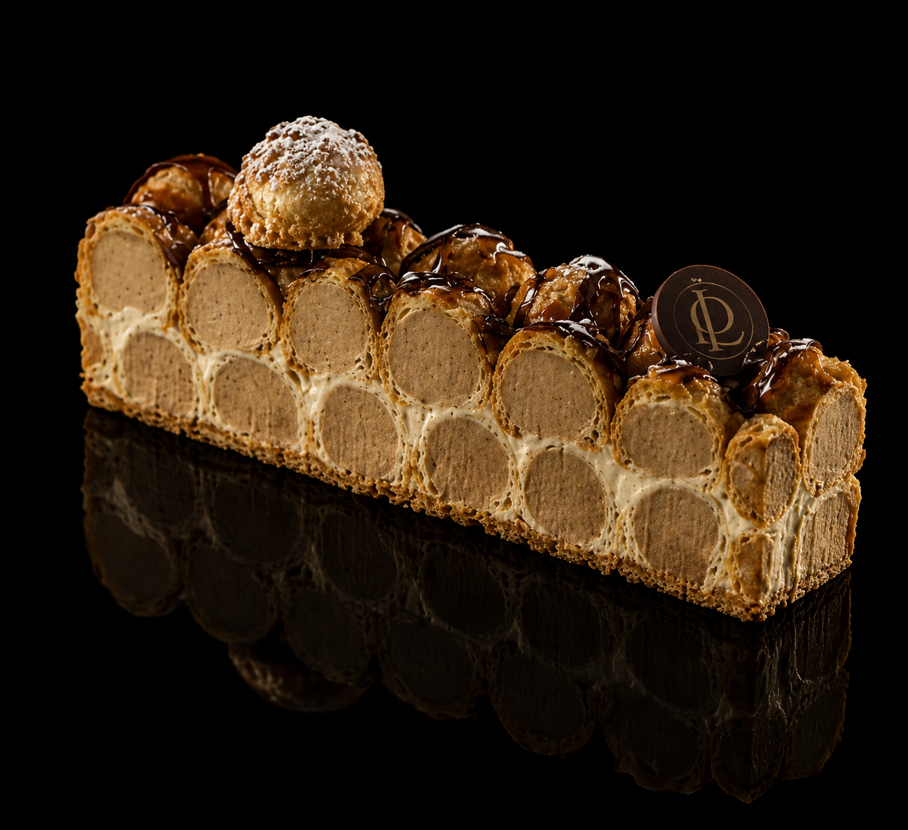 Gâteau de dessert avec des Boules de biscuit chaud, décoré de sauce au chocolat et d'une petite boule de crème, avec un logo d'une marque de pâtisserie.