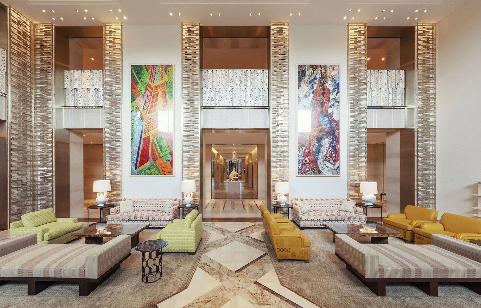 Hall d'hôtel moderne avec canapés, lampes et œuvres d'art colorées sur le mur.