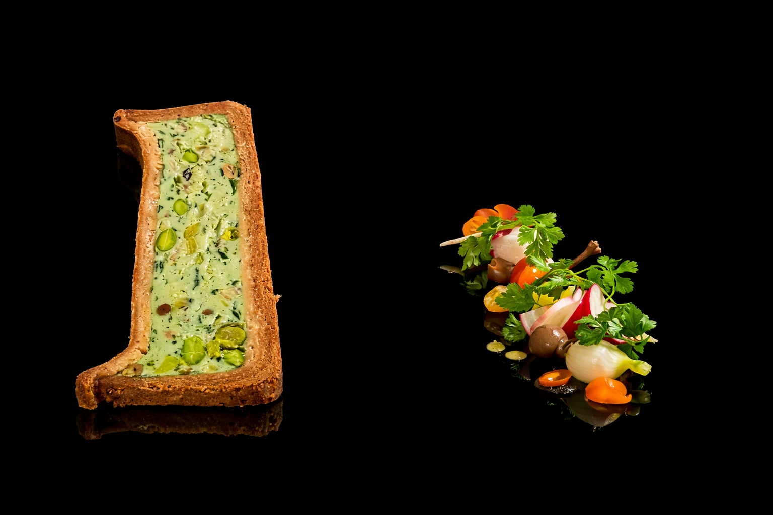 Une tarte salée avec une garniture verte contenant des légumes, placée à gauche, et un assortiment de légumes frais avec des herbes à droite, tous sur un fond noir.