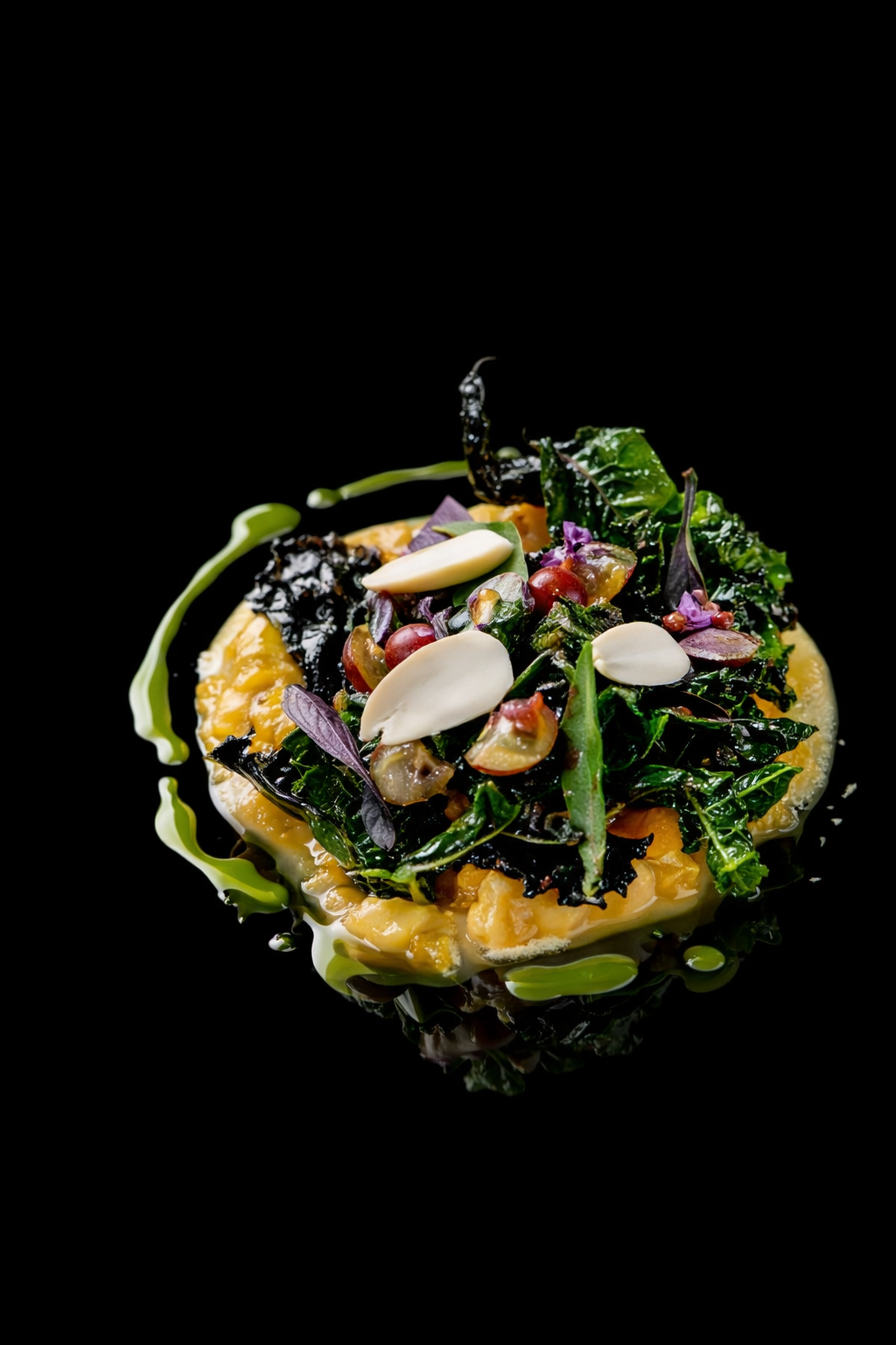Assiette gastronomique avec légumes verts, graines, noix, des tranches de fromage, et une sauce sur un fond noir