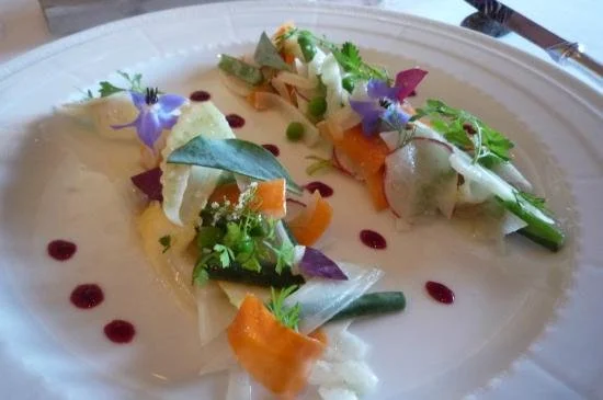 Assiette gastronomique avec légumes, fleurs comestibles, et sauce décorative