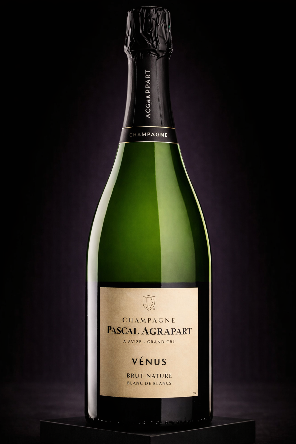 Bouteille de champagne Pascal Agrapart Vénus, brut nature, sur un fond noir avec éclairage mettant en valeur l'étiquette beige et le cola vert de la bouteille.