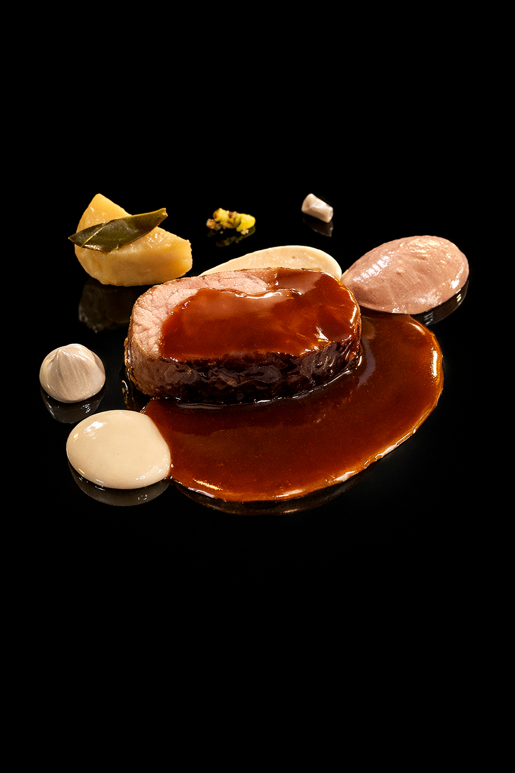 Assiette de viande en sauce avec divers accompagnements, présentée élégamment sur un fond noir.