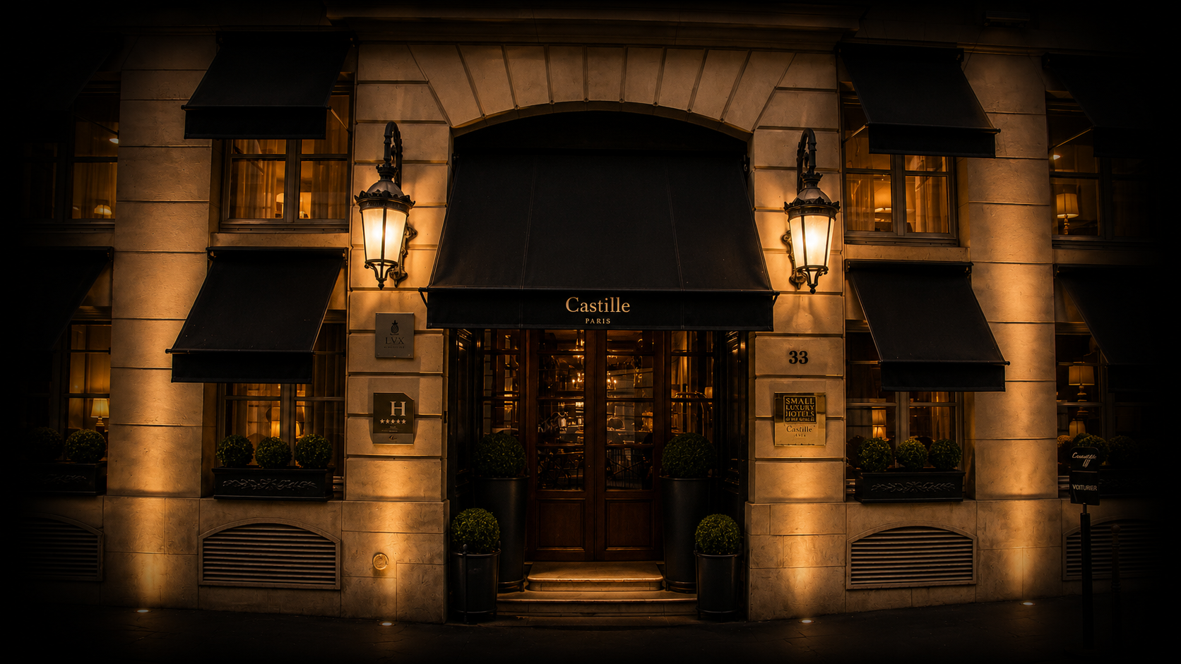 Façade d'hôtel élégant à Paris, avec éclairage chaleureux, fenêtres à volets noirs, et un porche d'entrée avec une enseigne 'Castille'.