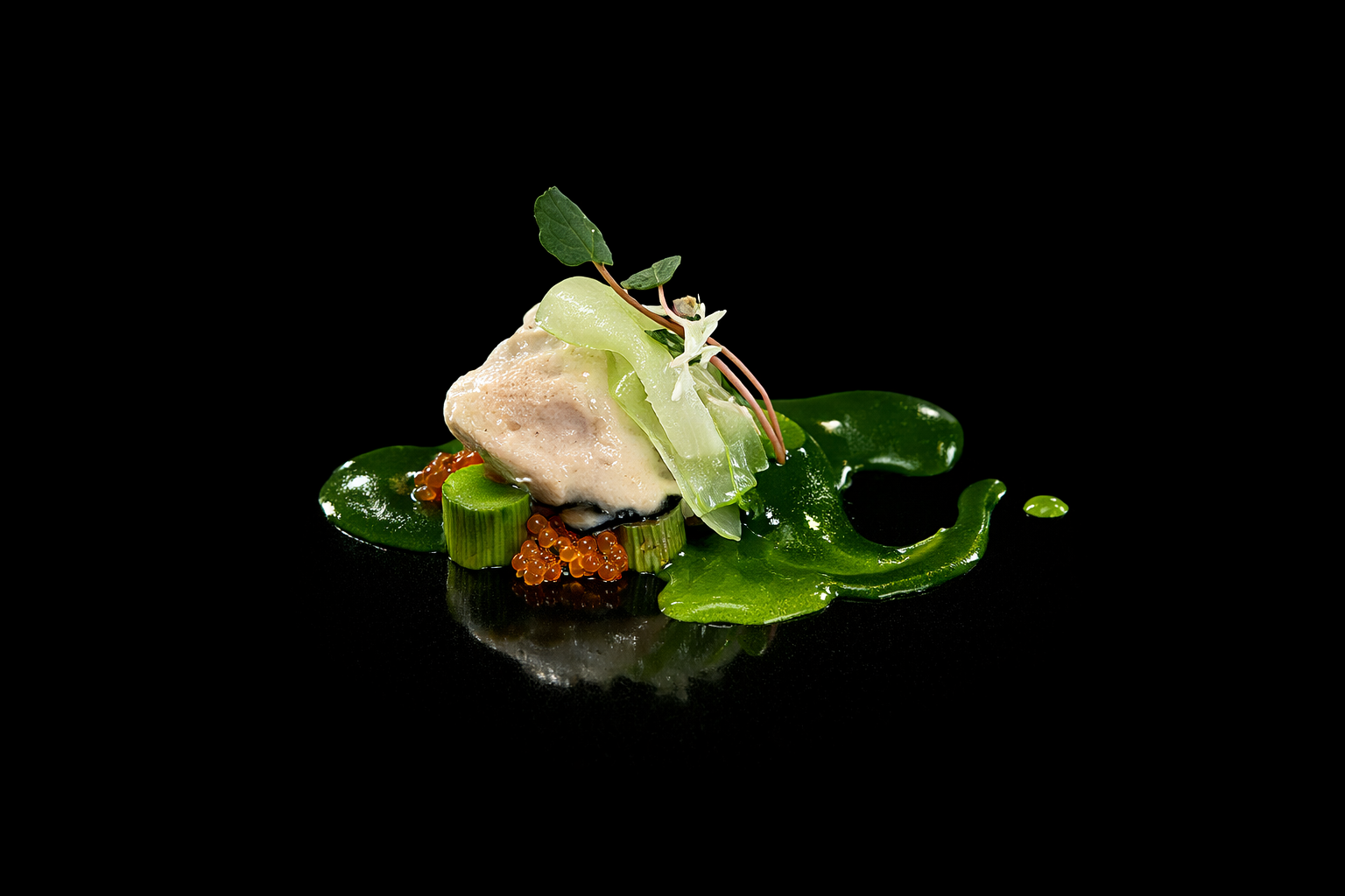 Un plat gastronomique sophistiqué avec une mousse ou tartare, garni de caviar orange, feuilles vertes et decorative, présenté sur un fond noir.