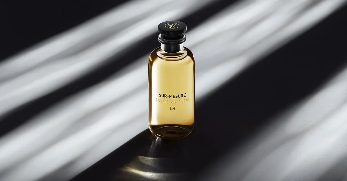 Flacon de parfum doré de Louis Vuitton sur un fond sombre avec des rayures de lumière
