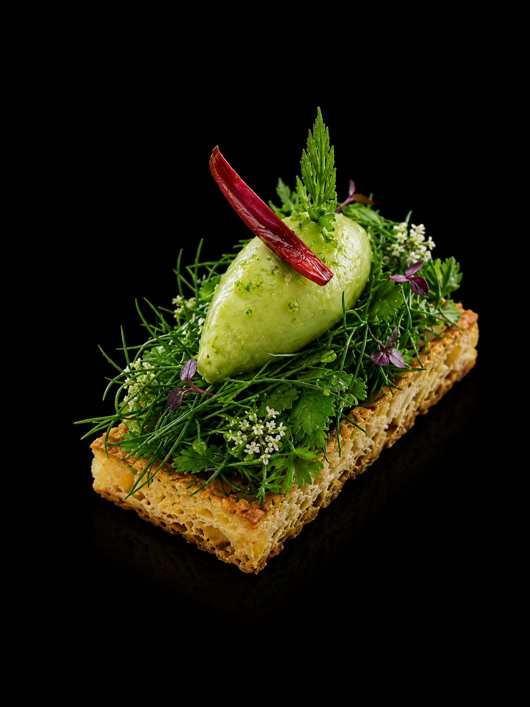 Plats de nourriture élaborée avec une base croustillante, garnie de légumes verts frais et d'un sorbet ou mousse verte, décoré avec une tranche de piment rouge.