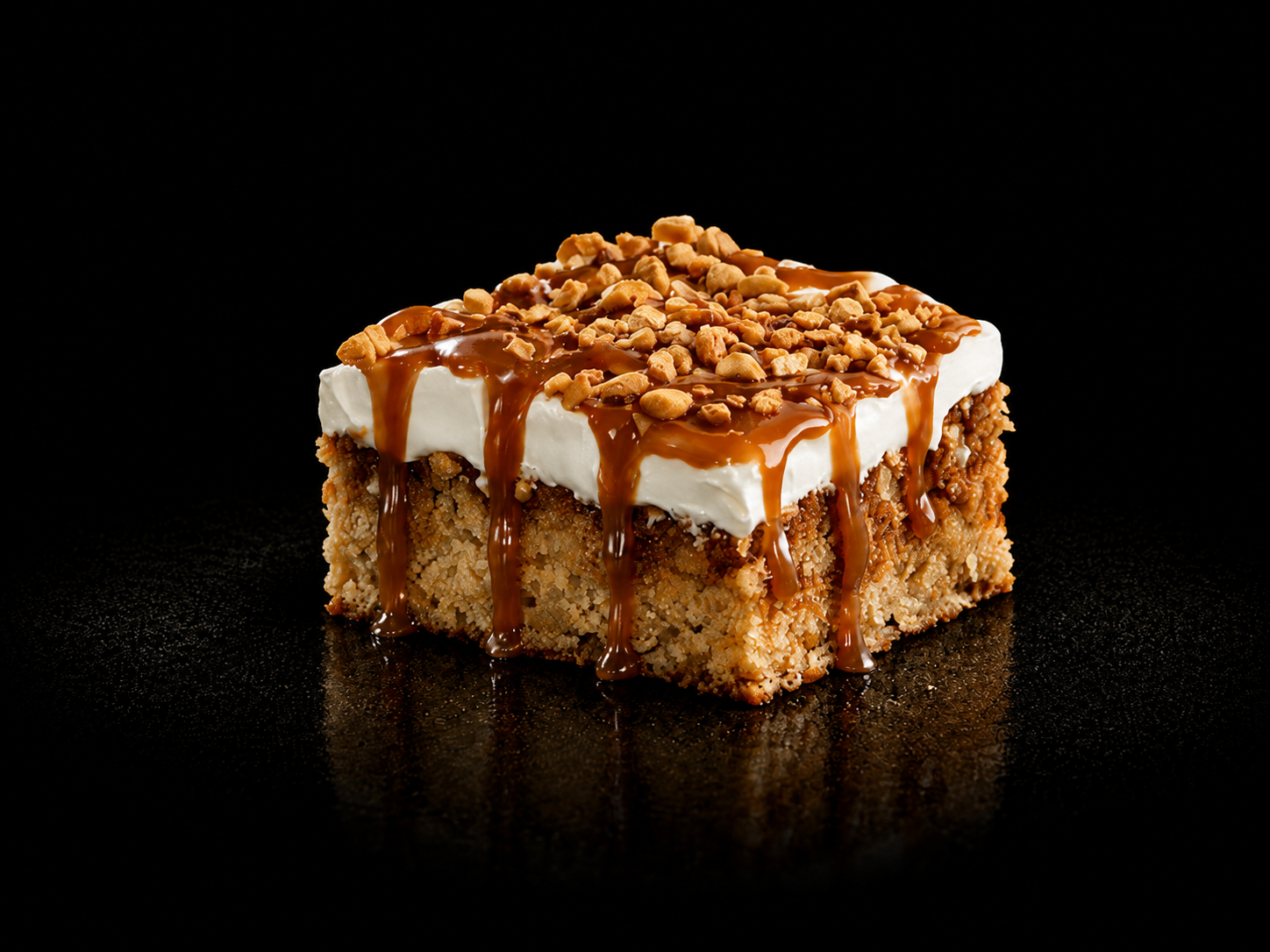 Gâteau en carré avec une couche de crème, des noix, du caramel et des morceaux de biscuit ou de céréale.