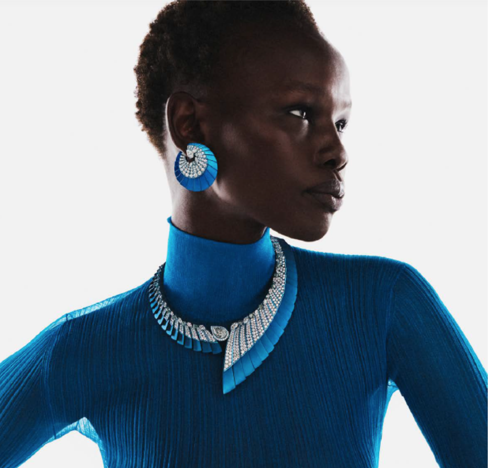Portrait d'une femme noire portant une tenue bleue, des bijoux brillants, et une boucle d'oreille bleue.