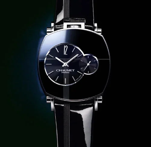 Montre noire avec un cadran rond, marque Chaumet, Paris, avec deux aiguilles et un sous-cadran.