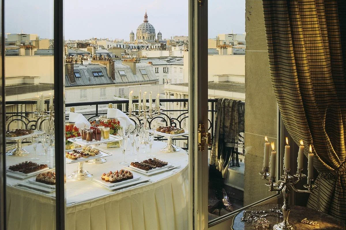 Retour de balcon avec table de repas organisée pour un dîner, avec des desserts, des bougies et un panorama de la ville avec une grande coupole en arrière-plan.