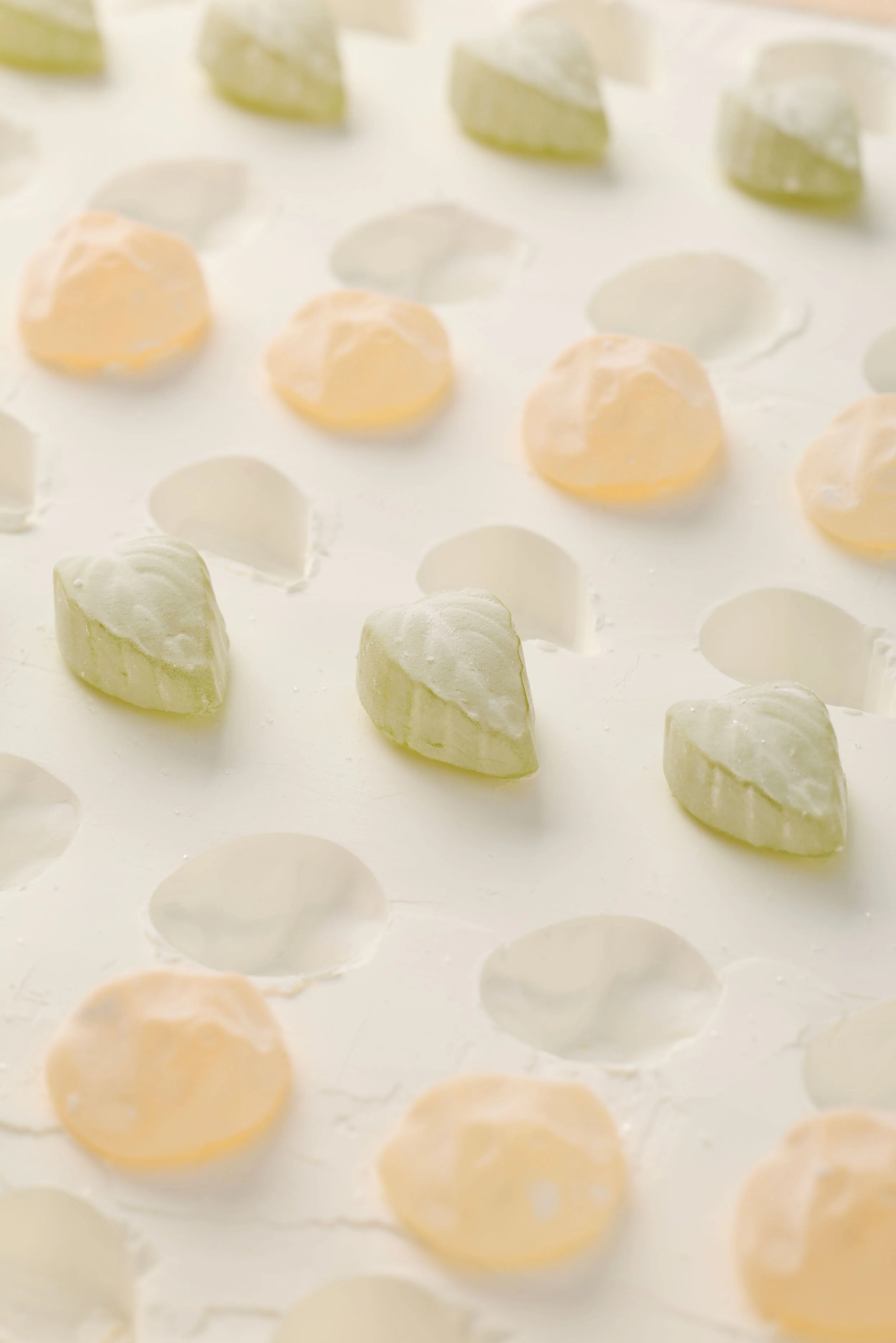 Gâteau en cours de décoration avec des petits morceaux de glaçage coloré en vert et beige sur une plaque de cuisson