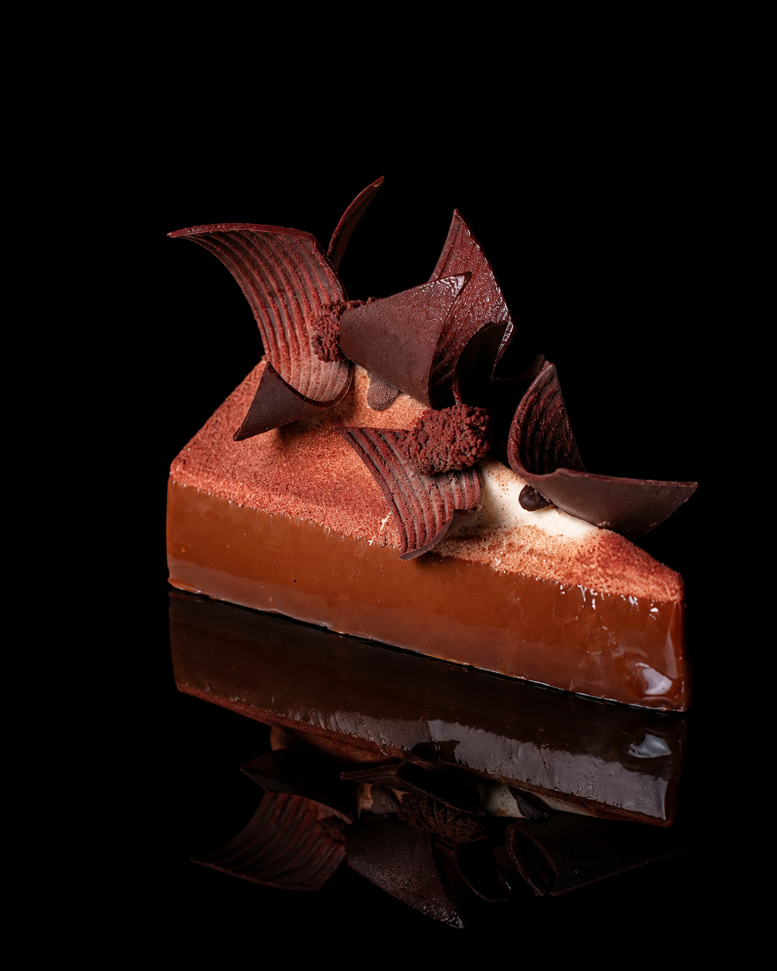 Partie d'une tarte au chocolat décorée de copeaux de chocolat et de formes de chocolat.