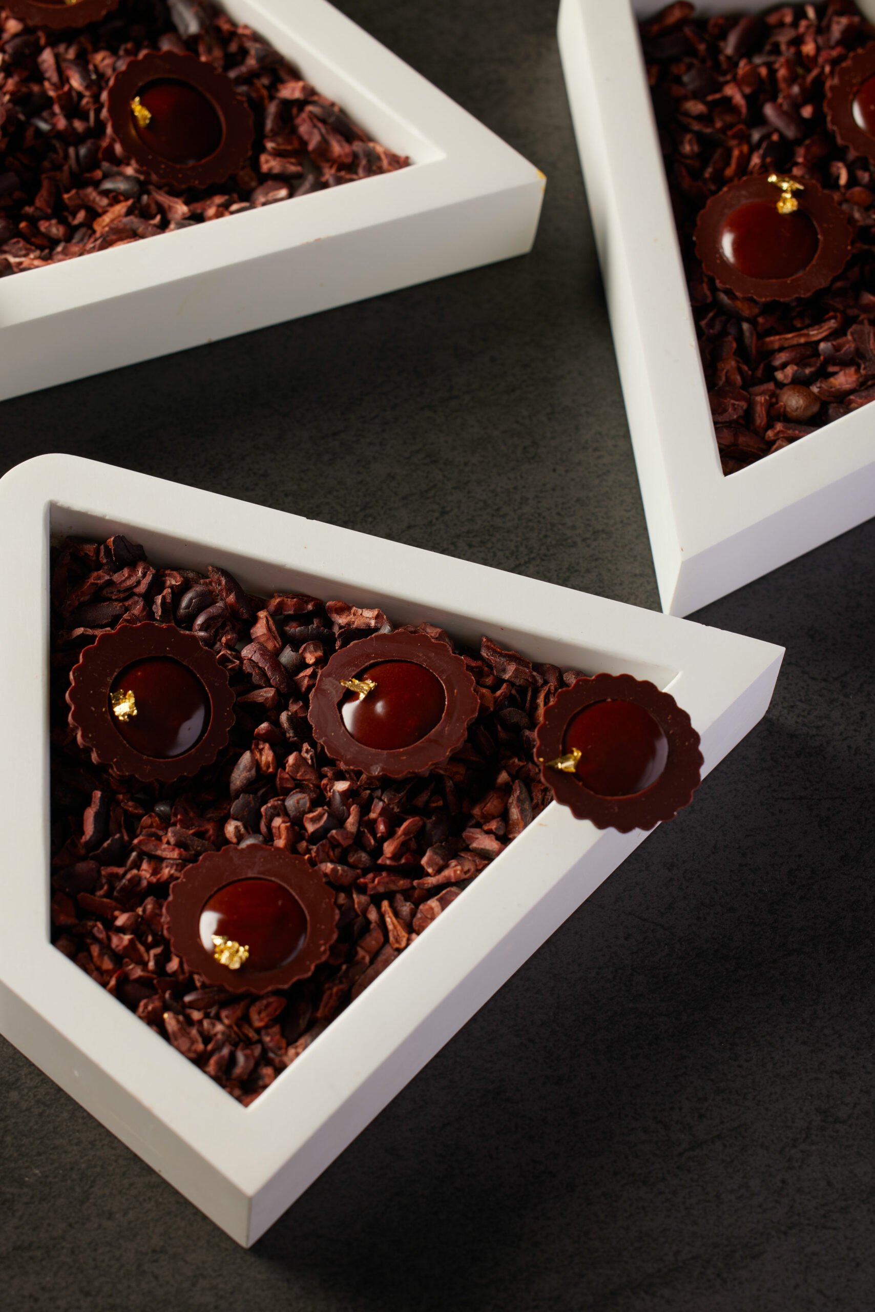 Boîte blanche de chocolats garnis de ganache, posée sur un fond noir
