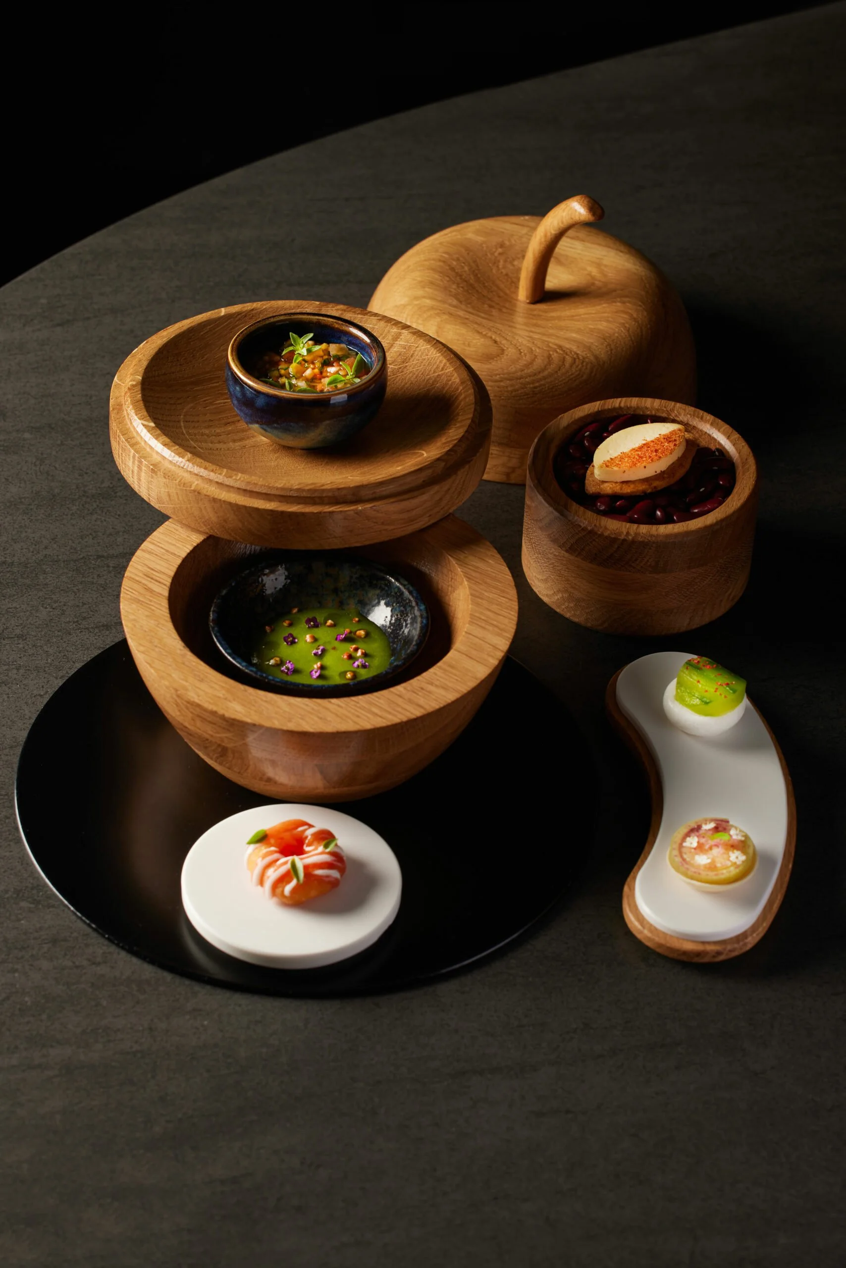 Assortiment de petits plats en céramique et en bois, présentation élégante avec un thème moderne et artistique, sur une surface noire