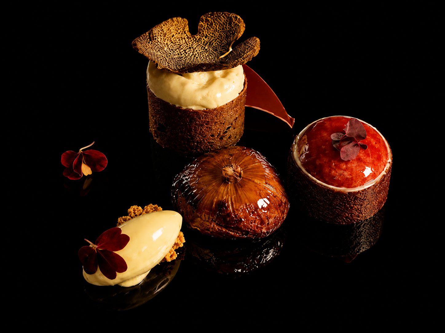 Gâteaux élégants avec des décorations en chocolat, confitures et fleurs comestibles sur un fond noir.