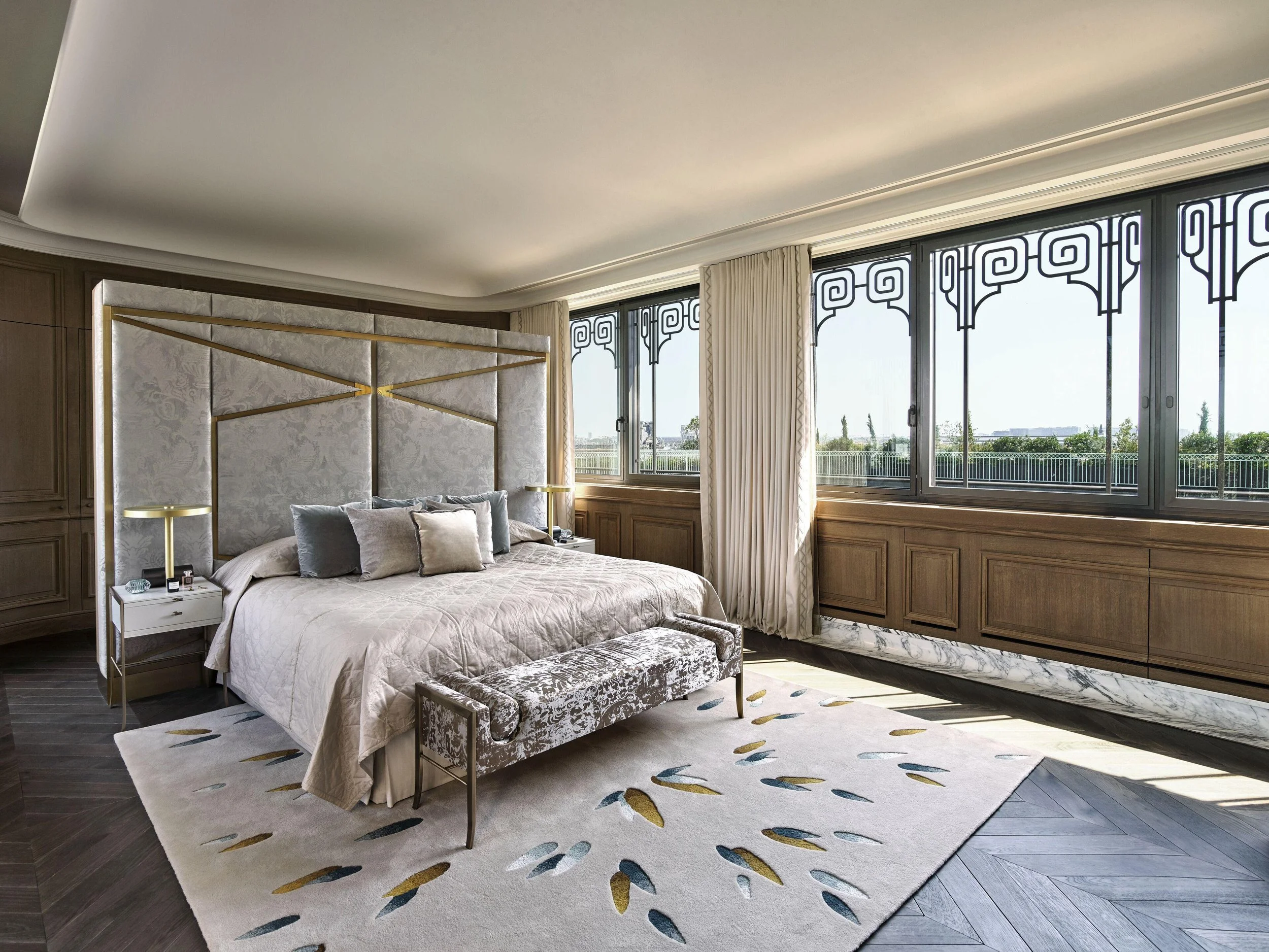 Chambre élégante avec un lit king-size, un tapis moderne, de grands fenêtres offrant une vue extérieure, et un décor sophistiqué.
