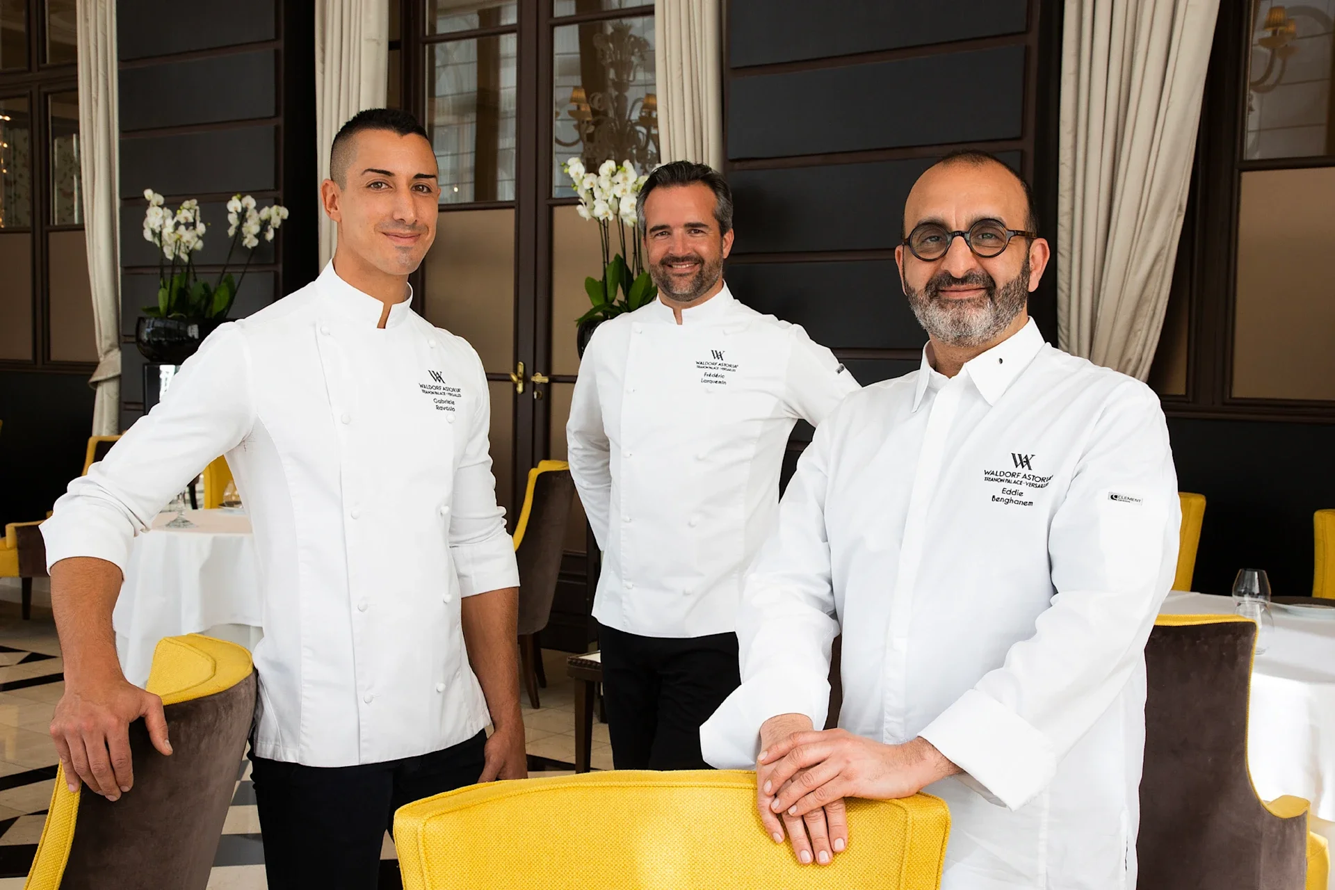 Trois chefs en uniforme blanc dans un restaurant élégant.