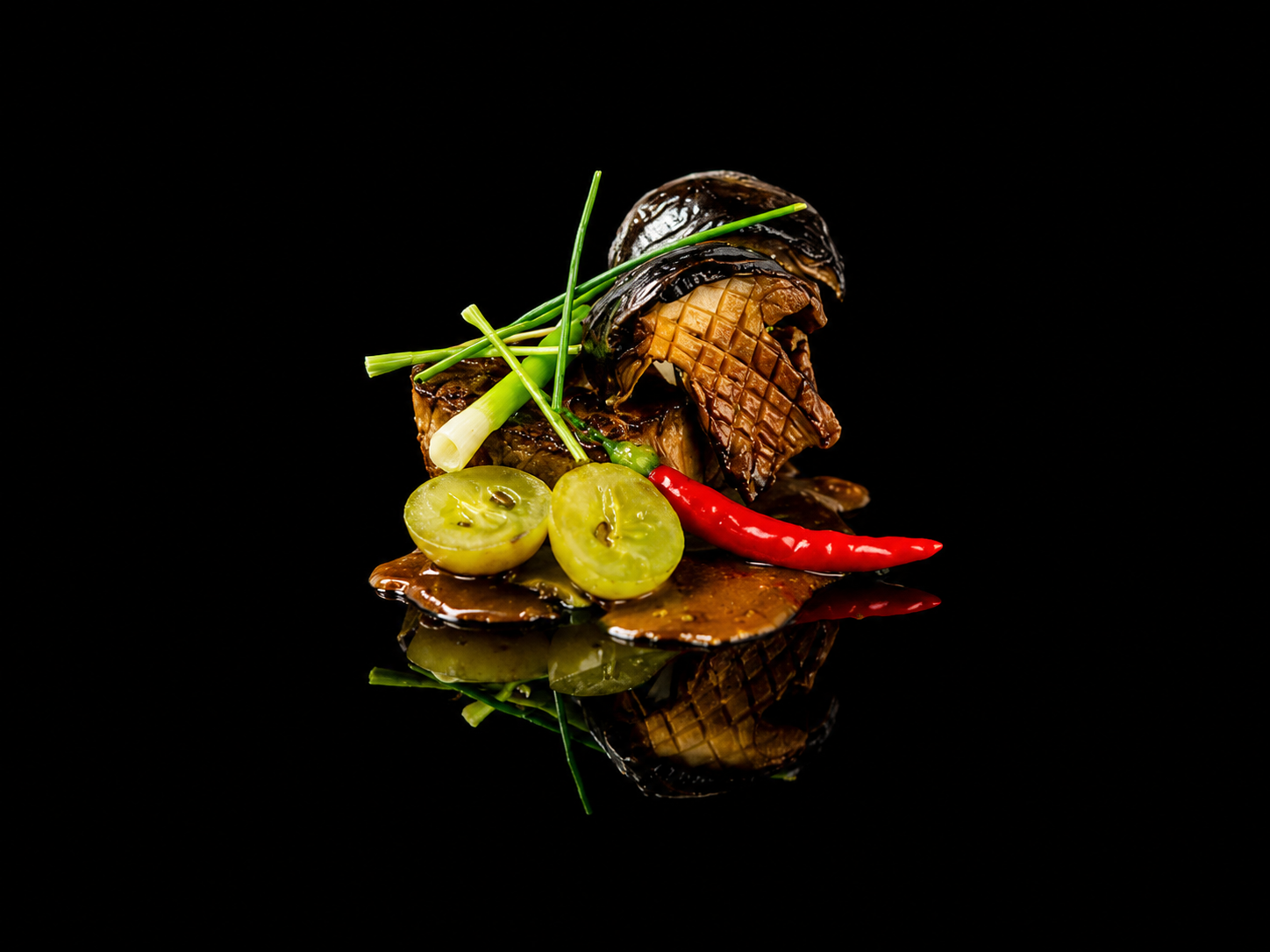 Plat de viande grillée avec des oignons verts, groseilles et un piment rouge, présenté sur une surface noire.
