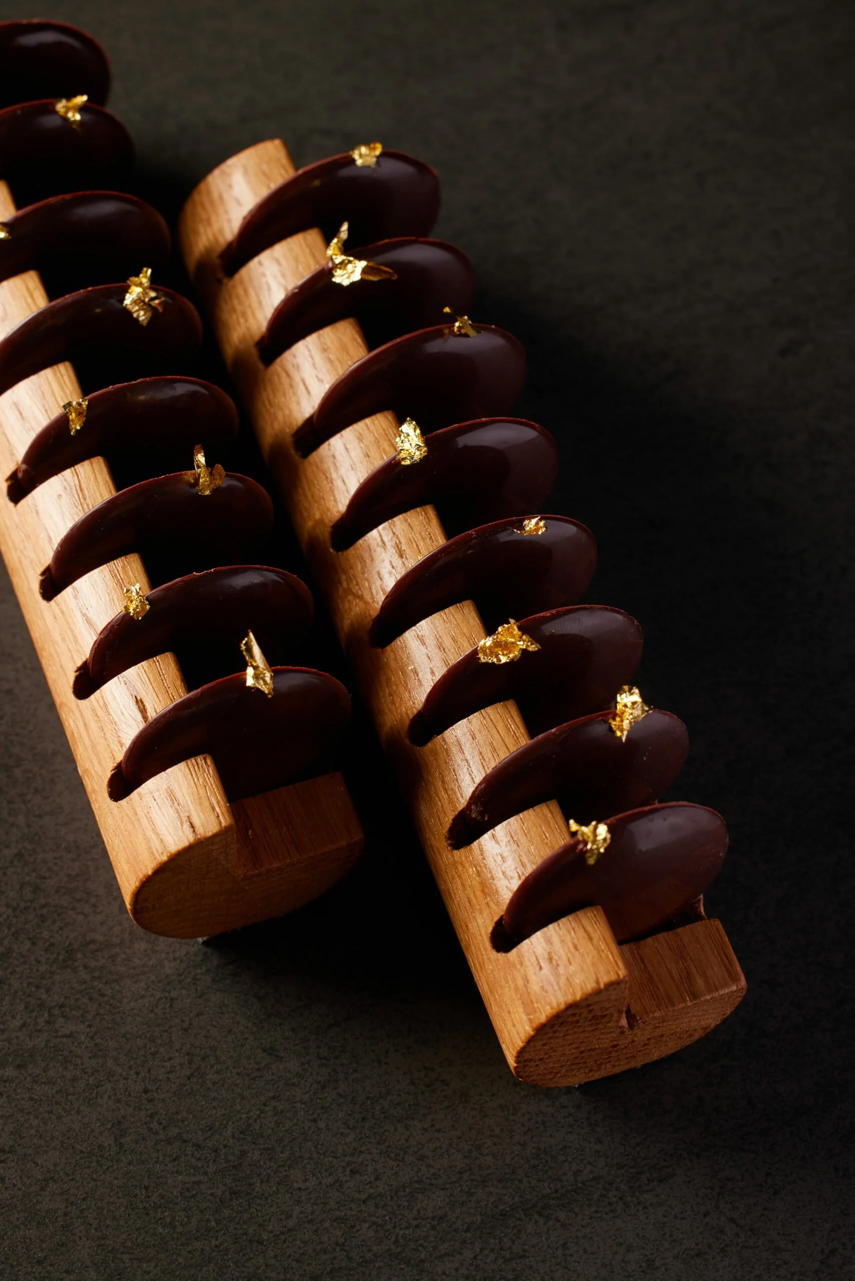 Gâteaux en forme de croissants avec de l'or comestible, disposés sur un support en bois