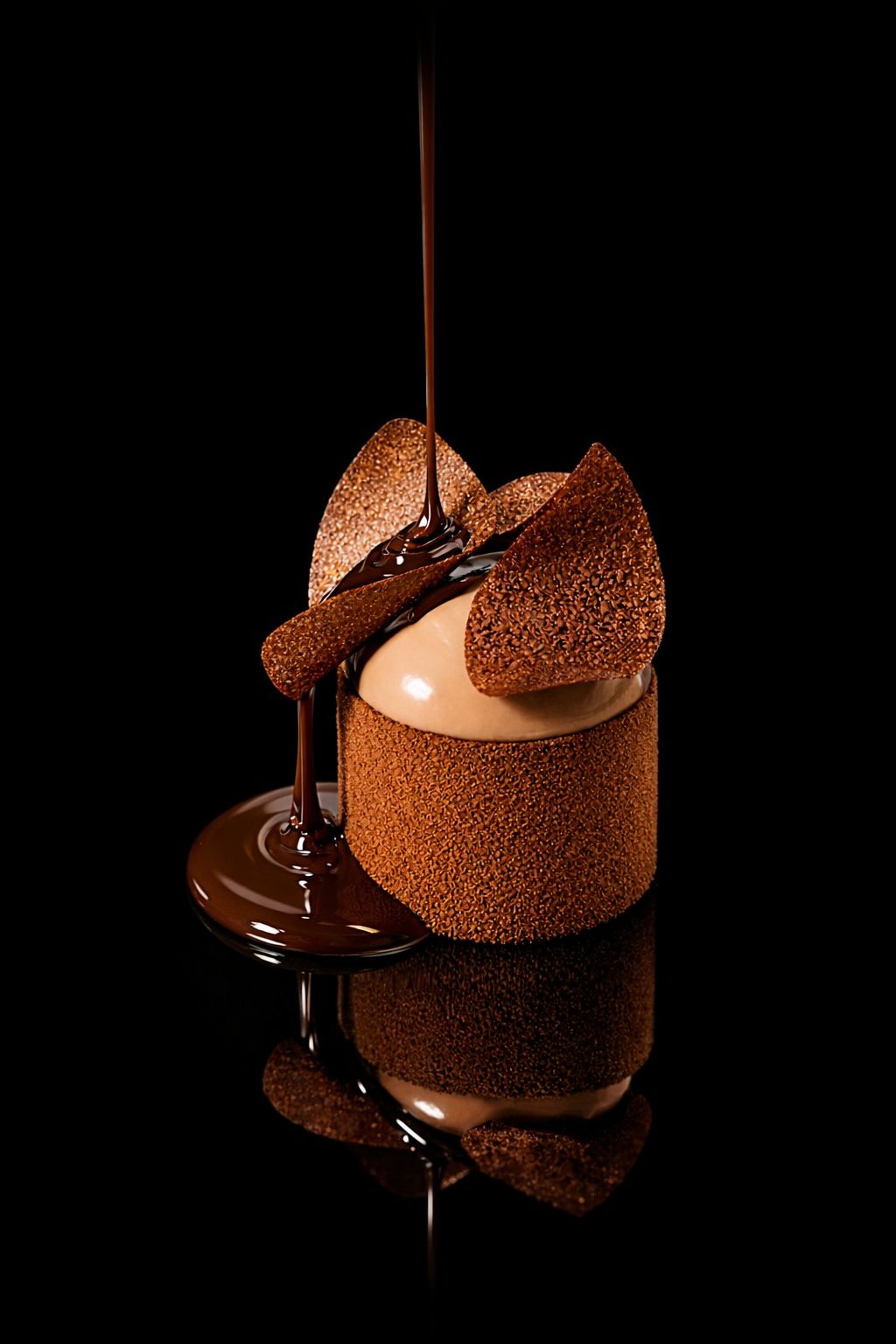 Un gâteau au chocolat décoré avec des croustillants en forme de triangles, une glace à la vanille, et du chocolat fondu versé au centre.