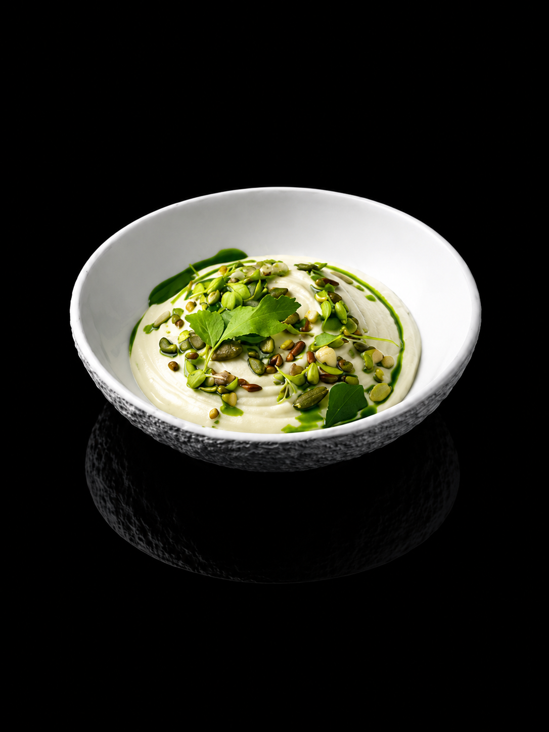 Bol de yaourt nature avec des graines diverses, des feuilles de persil, et une sauce verte, sur fond noir.
