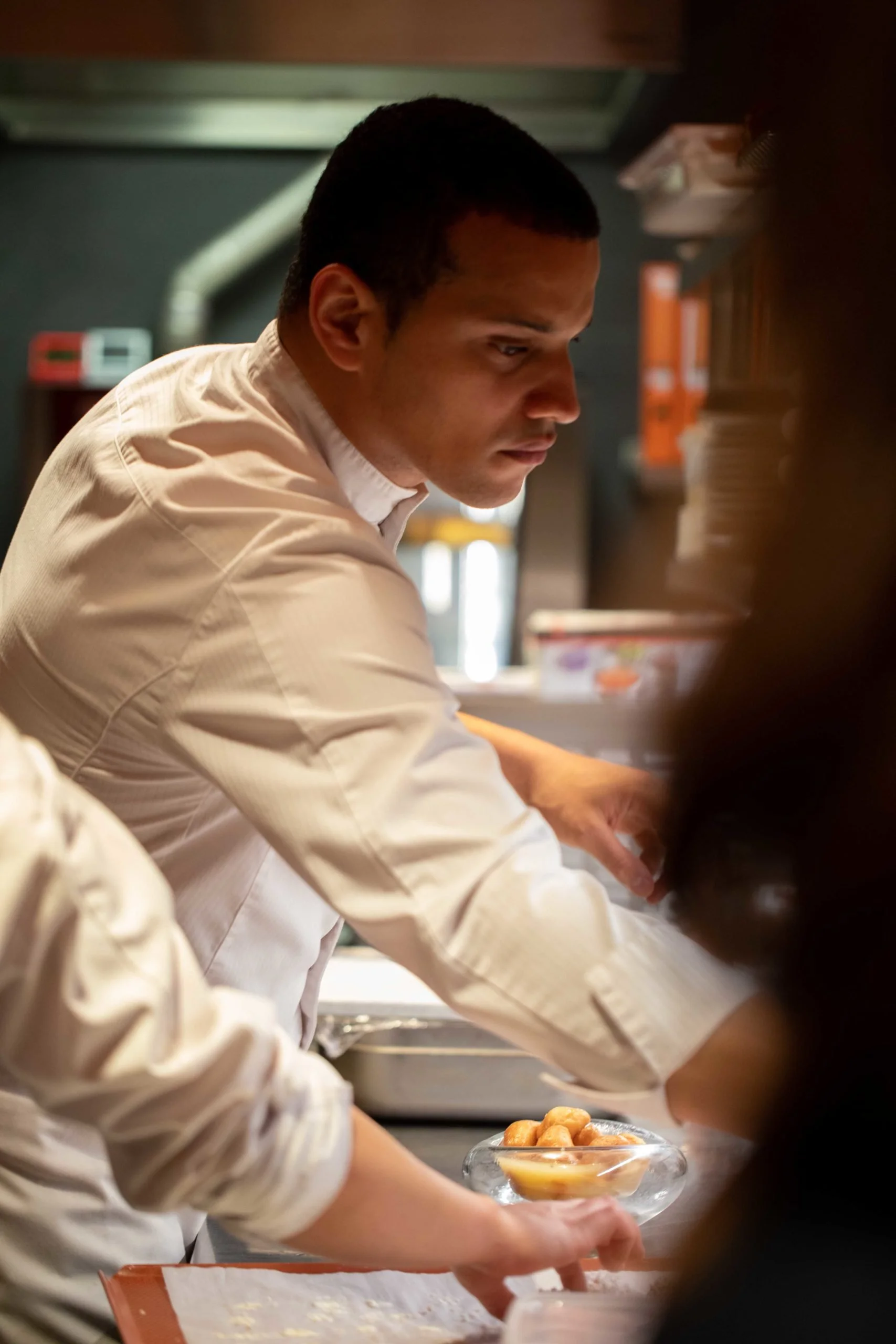 Un chef en uniforme blanc préparant des plats dans une cuisine professionnelle.