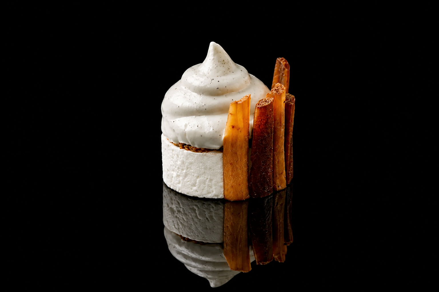 Dessert avec une crème chantilly sur un fond noir, entouré de bâtons de caramel.