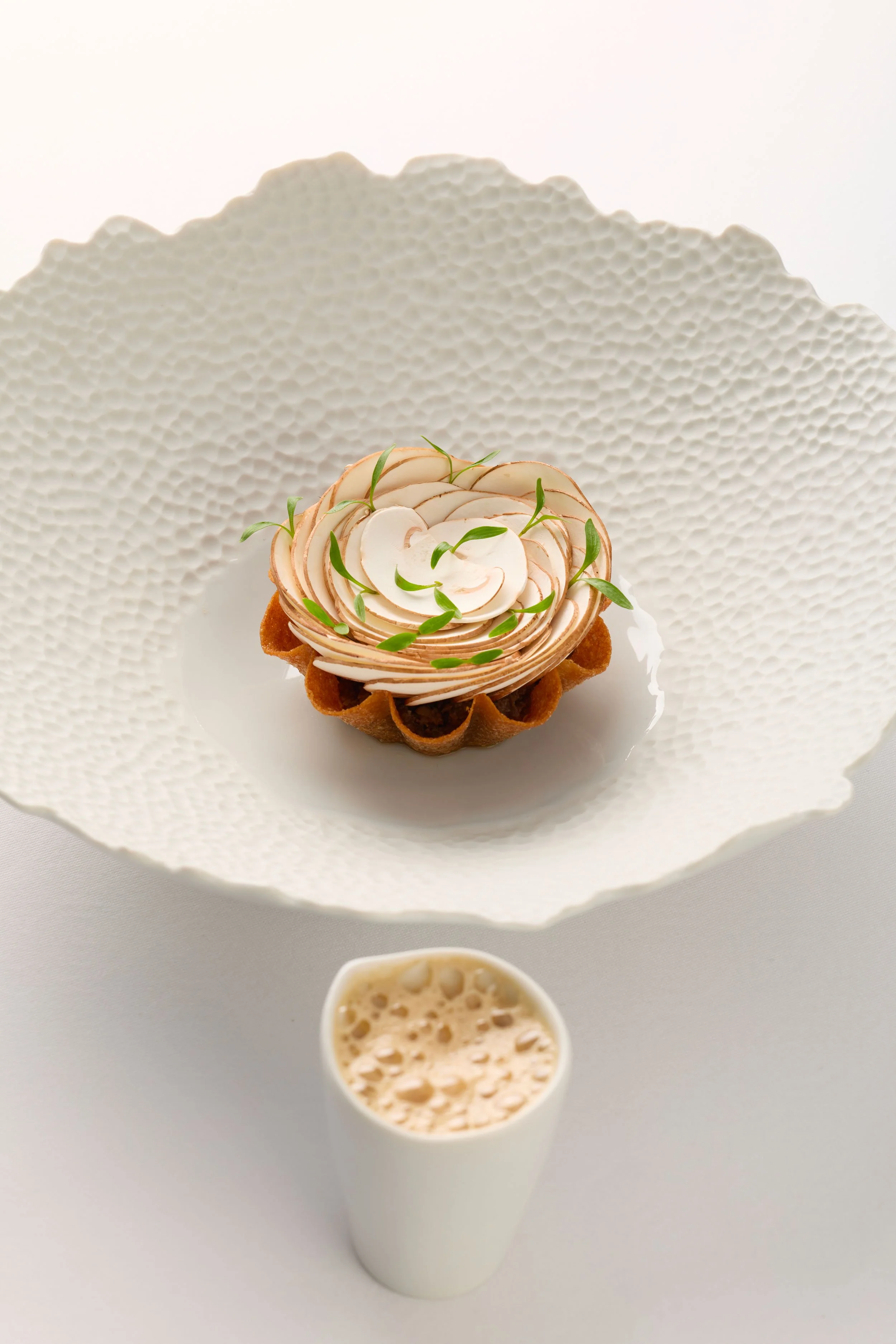 Dessert en pâte feuilletée avec crème et décoration verte, accompagnée d'une boisson dans un petit verre